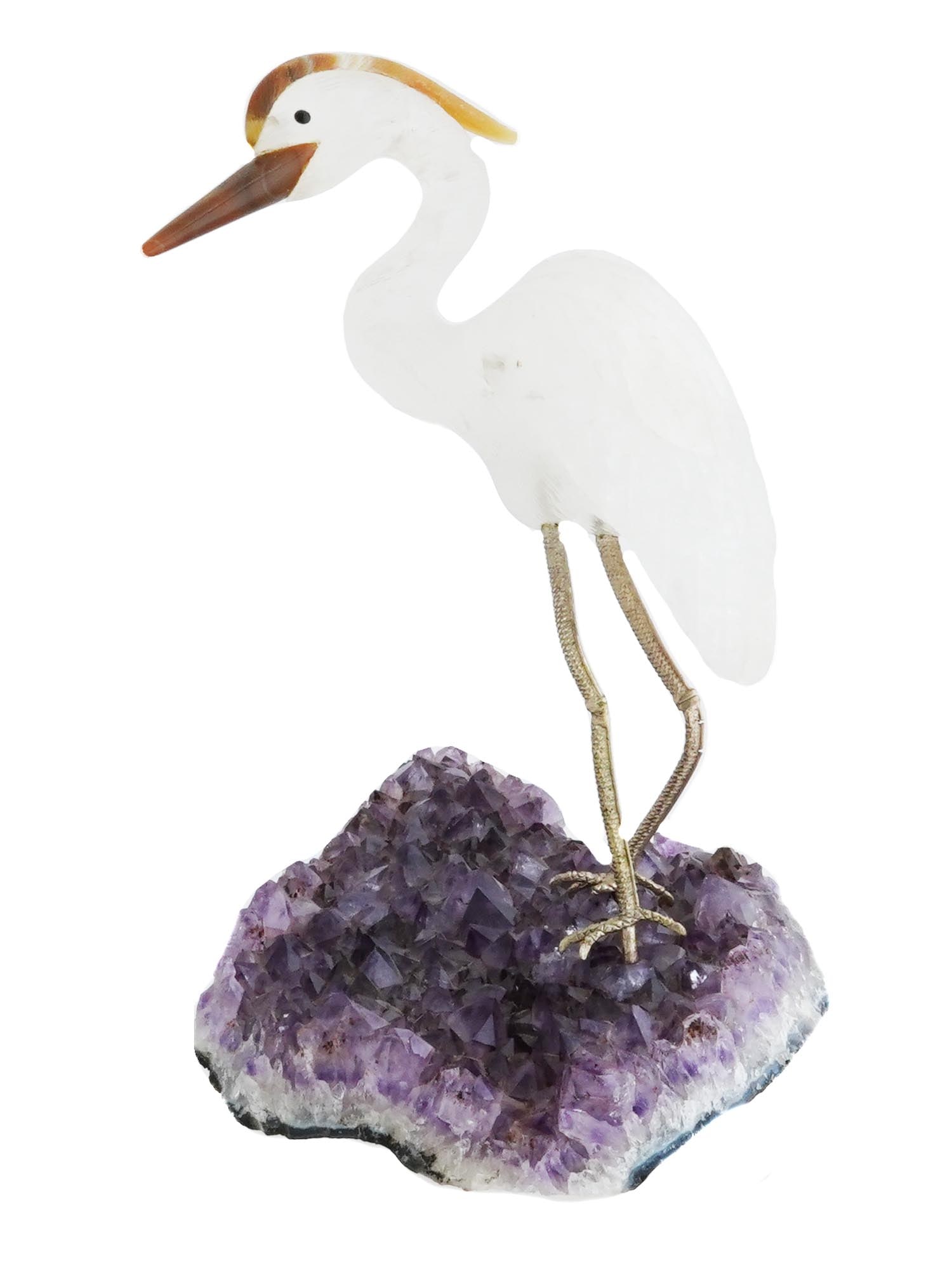 ROCK CRYSTAL AND AGATE BIRD SCULPTURE ON AMETHYST BASE: A hand carved rock crystal heron bird sculpture engraved with detailed patterns. The birds beak and crest are made from agate. The bird stands on a large, natural amethyst geode base. The legs of the