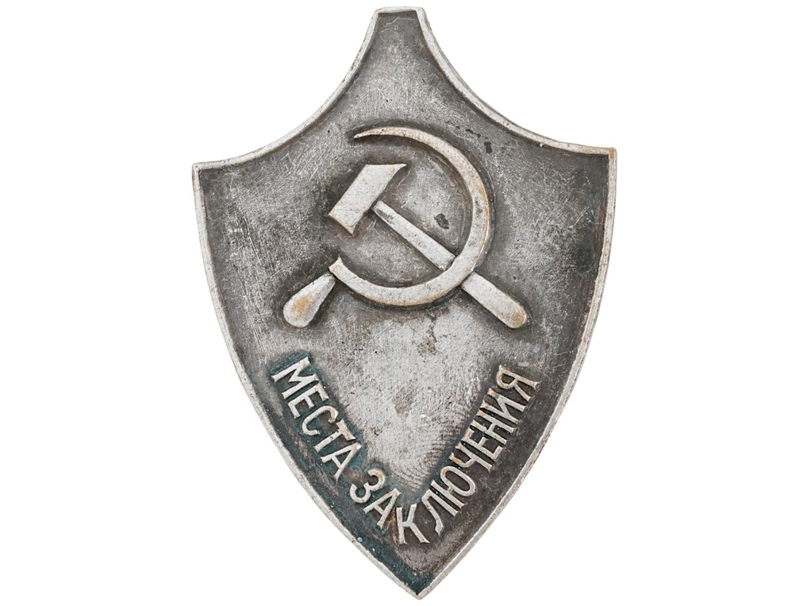 RUSSIAN SOVIET AWARD BADGE OF THE PLACE OF DETENTION: A Soviet era award badge of the Place of detention. Service badge for junior prison guards. Features a metal shield shaped badge with a hammer and sickle symbol at the top. Below the symbol, there is