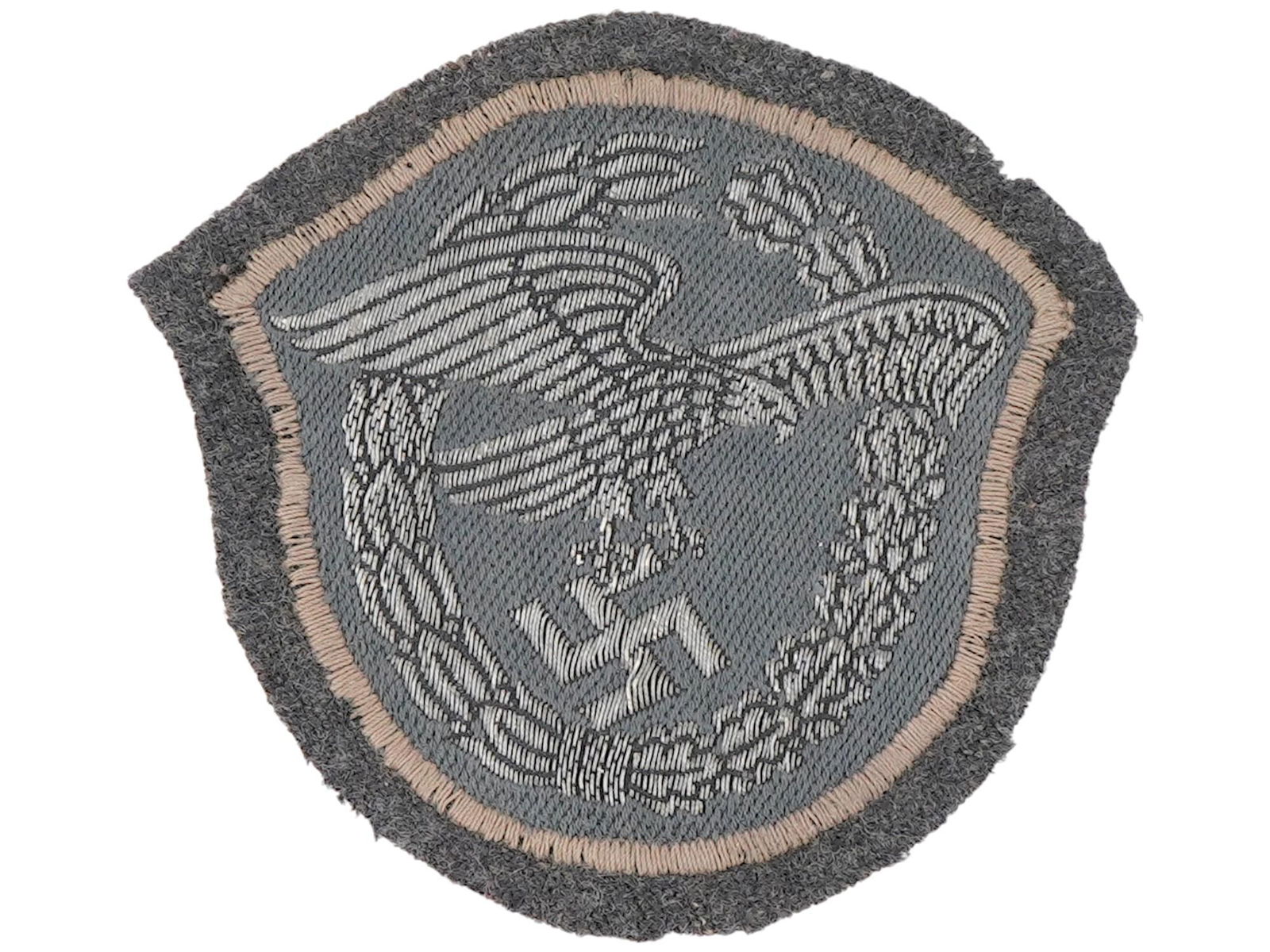 WWII NAZI GERMAN LUFTWAFFE EAGLE PATCH EMBROIDERED: A WWII Nazi German Luftwaffe eagle patch, embroidered in gray thread on a dark backing. This insignia features the iconic spread-winged Luftwaffe eagle clutching a swastika, typically worn on the unif