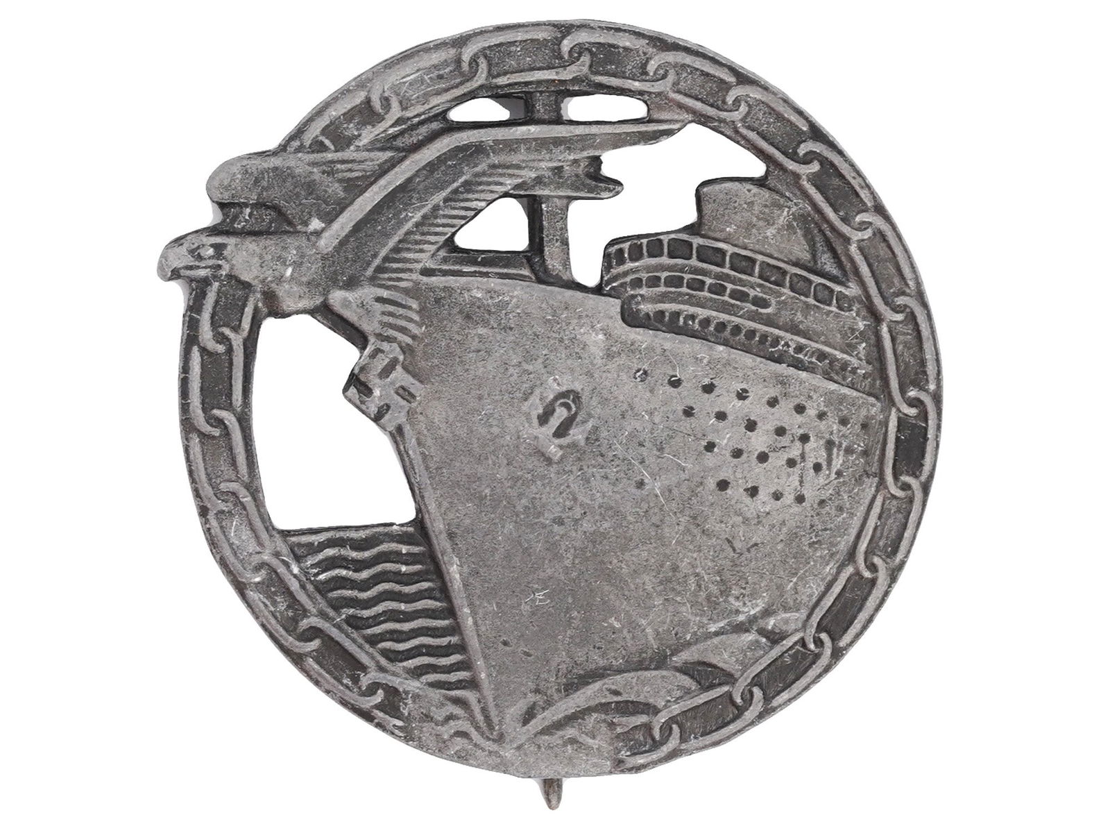 WWII NAZI GERMAN 3RD REICH BLOCKADE RUNNER BADGE: A WWII Nazi German Blockade Runner badge. The round badge features a chain around the edge and an image of a German warship sailing behind a flying eagle with a swastika. The Blockade Runner Badge, or