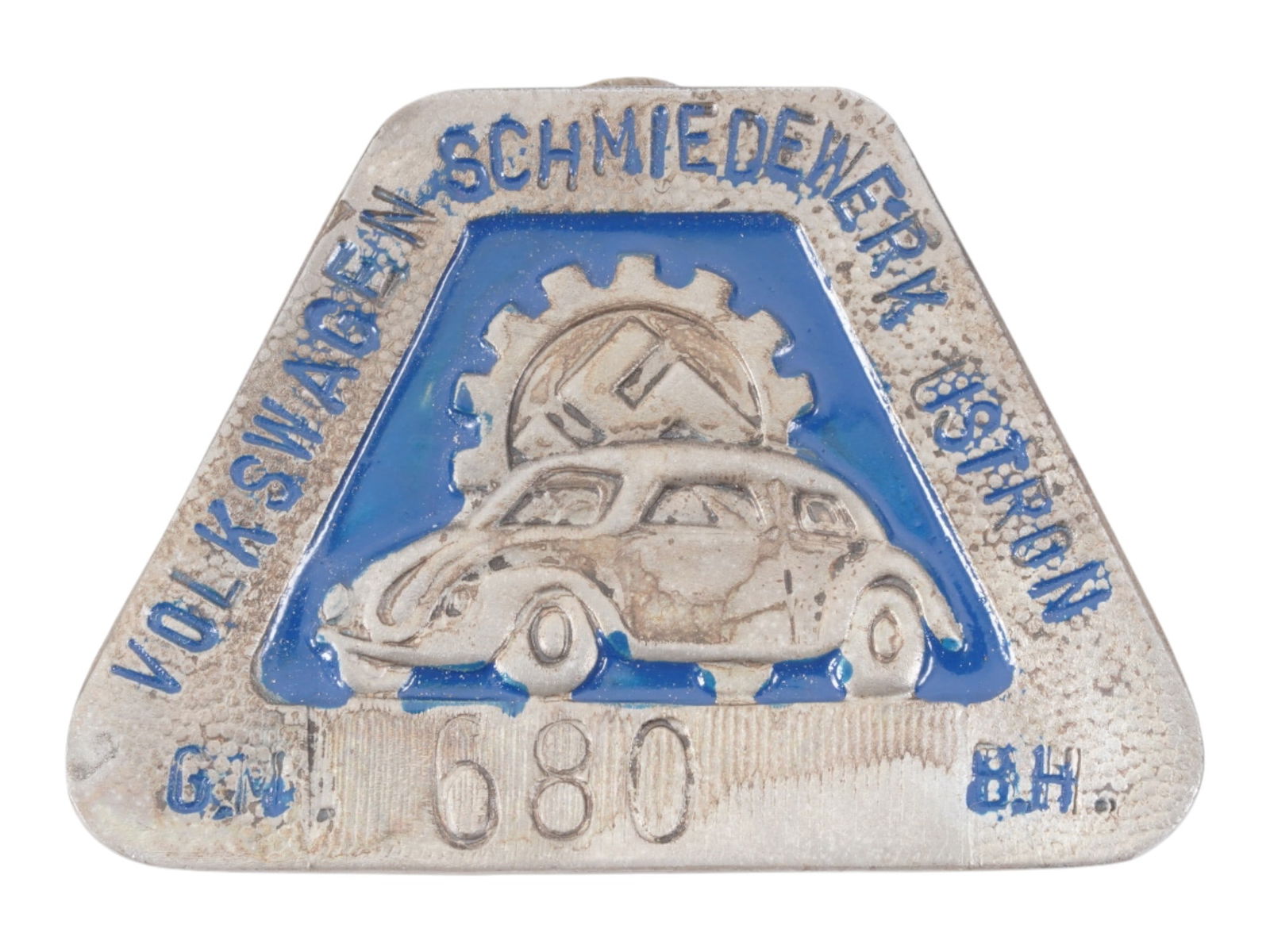 WWII TYPE GERMAN VOLKSWAGEN EMPLOYEE BADGE: A World War II type Nazi German enameled badge of Volkswagen factory employee. Schmiedewerk Ustron G.M. B.H., employees personal number 680, enameled blue. The badge features Nazi party symbols. Volks