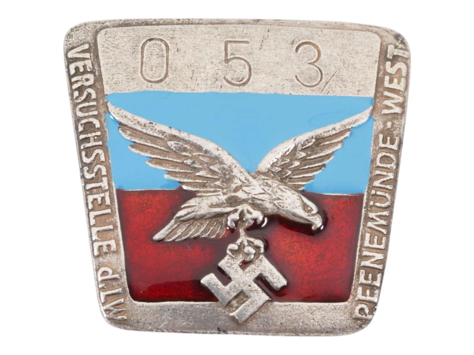 WWII TYPE GERMAN PEENEMUNDE V-2 EMPLOYEE BADGE: A World War II type Nazi German enameled badge of Peenemunde V-2 factory employee. Versuchsstelle d. LW Peenemunde West, employees personal number 053, enameled blue and red. In World War II, the Peen