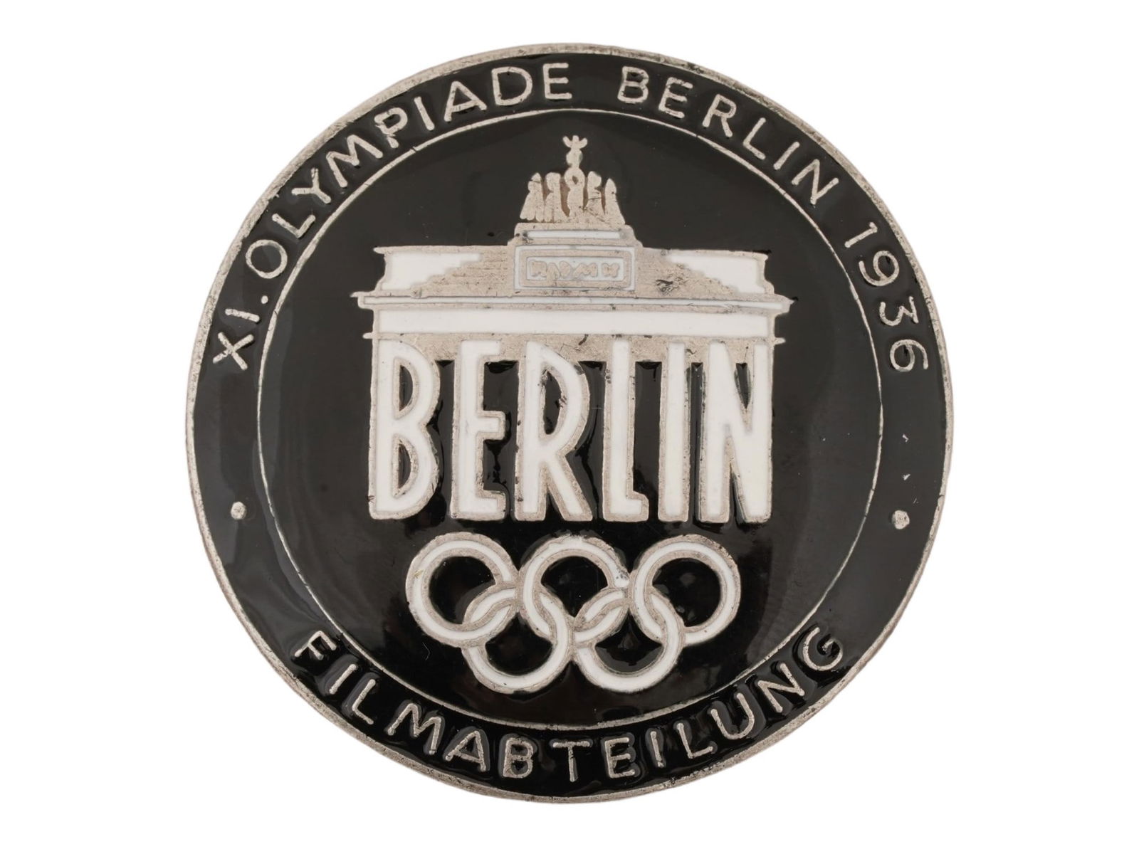 WWII TYPE GERMAN BERLIN OLYMPIC GAMES FILMMAKER BADGE: A WWII type Nazi German 1936 Berlin Olympics Filmmaker pin badge. Features the Brandenburg Gate with the inscription Berlin and the Olympic Rings below, and covered with enamel in black and white shad