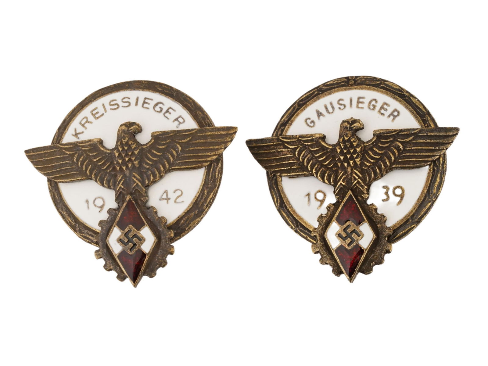 LOT OF TWO WWII TYPE GERMAN HITLER YOUTH BADGES: A lot of two WWII type German Hitler Youth 1942 Kreissieger and 1939 Gausieger badges. The first features a national eagle clutching a cogwheel with an enameled HJ diamond in its talons, with KREISSIE