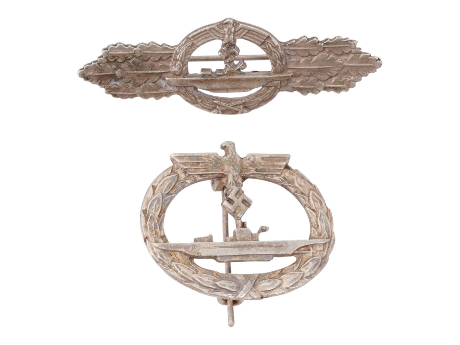 LOT OF NAZI GERMAN TYPE WWII U BOAT BADGE AND CLASP: A lot of a WWII Nazi German type U Boat badge and a U Boat clasp. The wares are decorated with an image of a boat and a Nazi eagle swastika insignia, and oak leaves on the sides. Marked on the backsid