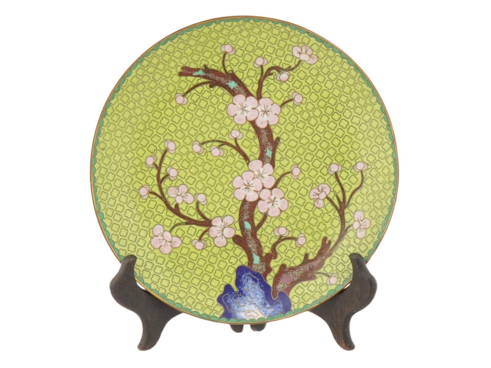 CHINESE CLOISONNE ENAMEL PLATE WITH STAND: A Chinese light green cloisonne enamel plate featuring a brown branch with pink blossoms against a background of a repeating geometric pattern. The back side is adorned with flower motifs. It is displ