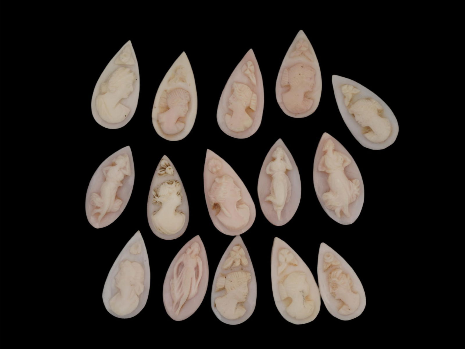 LOT OF 15 HAND CARVED CORAL CAMEOS WITH FEMALE FIGURES: A collection of 15 hand carved tear shaped coral cameos. Some represent female profiles in relief and some represent female figures. These carvings are typically made from natural coral, showcasing fi