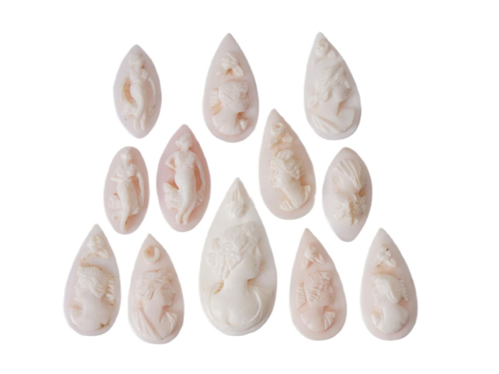 COLLECTION OF FEMALE PORTRAIT CARVED CORAL CAMEOS: A collection of hand carved pink coral cameos. A total of 12 items. Each piece depicts a female profile portrait rendered in high relief. Oval and drop shapes. Collectible Jewelry And Glyptic Art, Scu