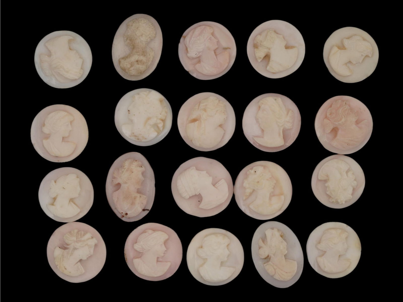 COLLECTION OF PORTRAIT CARVED CORAL STONE CAMEOS: A collection of hand carved pink Coral cameos. A total of 20 items. Each depicts a profile bust in relief, identified as a female portrait. The cameos are formed as small oval or circular shaped medal
