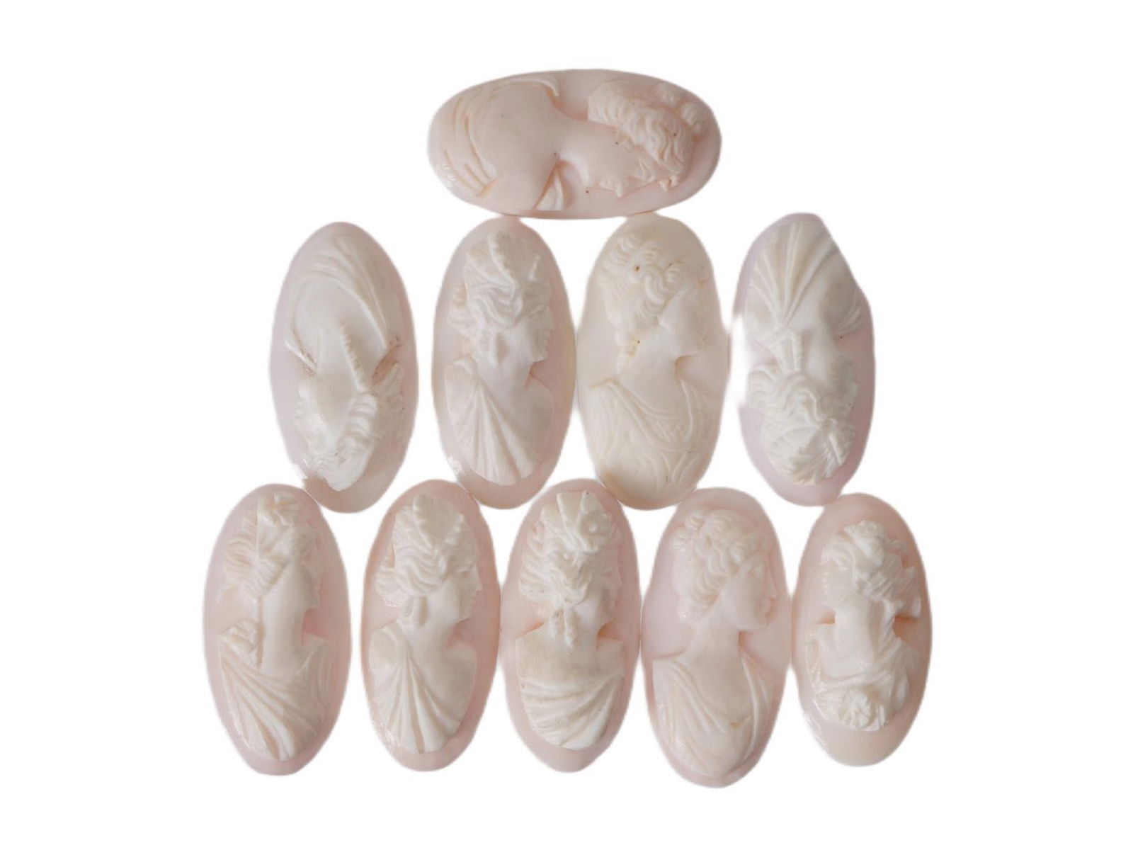 COLLECTION OF FEMALE PORTRAIT CARVED CORAL CAMEOS: A collection of hand carved pink coral cameos. A total of 10 items. Each piece depicts a female profile portrait rendered in high relief. Oval shape. Collectible Jewelry And Glyptic Art, Sculpture.