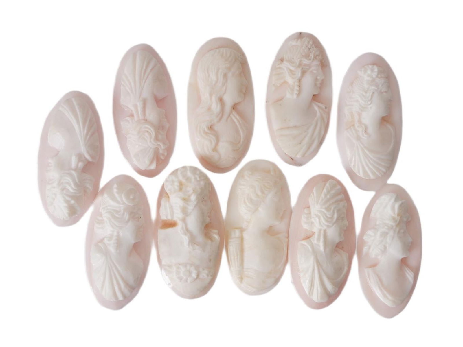 COLLECTION OF FEMALE PORTRAIT CARVED CORAL CAMEOS: A collection of hand carved pink coral cameos. A total of 10 items. Each piece depicts a female profile portrait rendered in high relief. Oval shape. Collectible Jewelry And Glyptic Art, Sculpture.