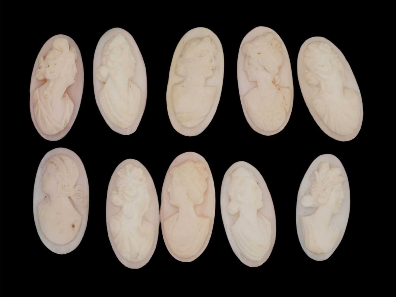 ANTIQUE VICTORIAN HAND CARVED CORAL CAMEO COLLECTION: A collection of 10 antique Victorian hand-carved coral cameos, showing a traditional form of relief sculpture and depicting various female profile portraits, likely intended for jewelry mounting or as
