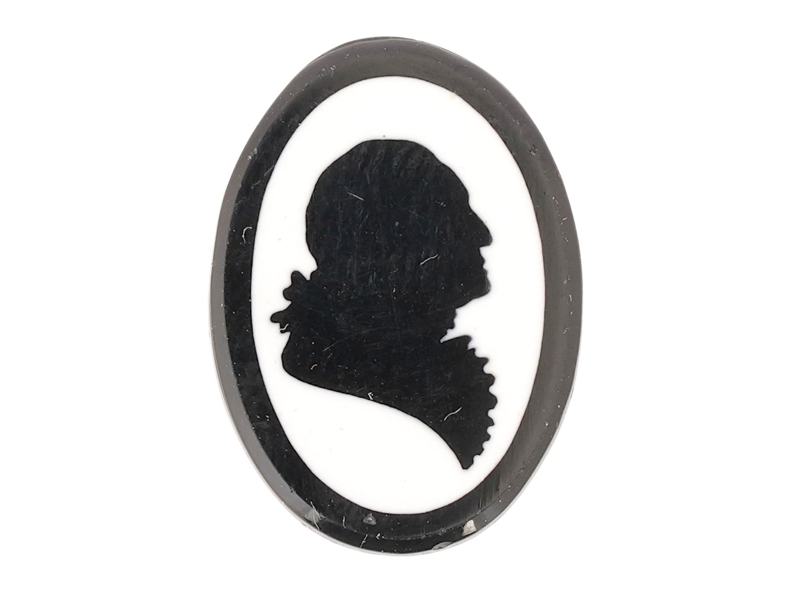 SILHOUETTE OF GEORGE WASHINGTON CARVED STONE CAMEO: An Art Deco manner oval shaped carved stone cameo features a finely carved silhouette of George Washington, set against a contrasting white background. The oval shaped silhouette captures the iconic p