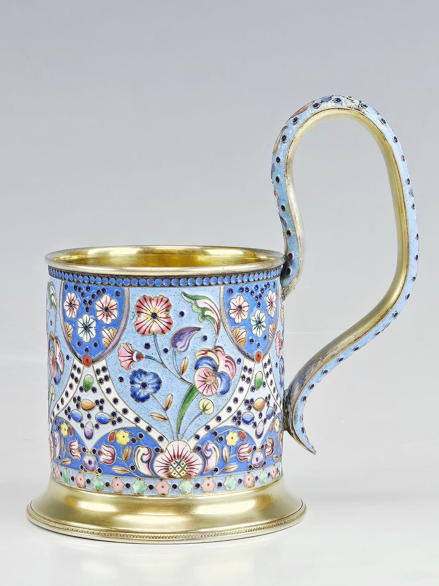 RUSSIAN GILT SILVER CLOISONNE ENAMEL TEA GLASS HOLDER: A Russian gilt silver and enamel tea glass holder, decorated with vibrant floral and geometric cloisonne motifs. The richly detailed design showcases the refined craftsmanship of late Imperial Russian