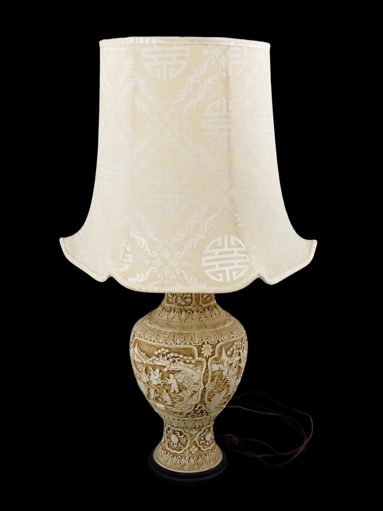 CHINESE CARVED CINNABAR STYLE VASE FORM TABLE LAMP: This table lamp features a cream-colored cinnabar-style resin body with deep relief carvings depicting traditional Chinese narrative scenes, including figures in a garden setting with a pagoda and mou