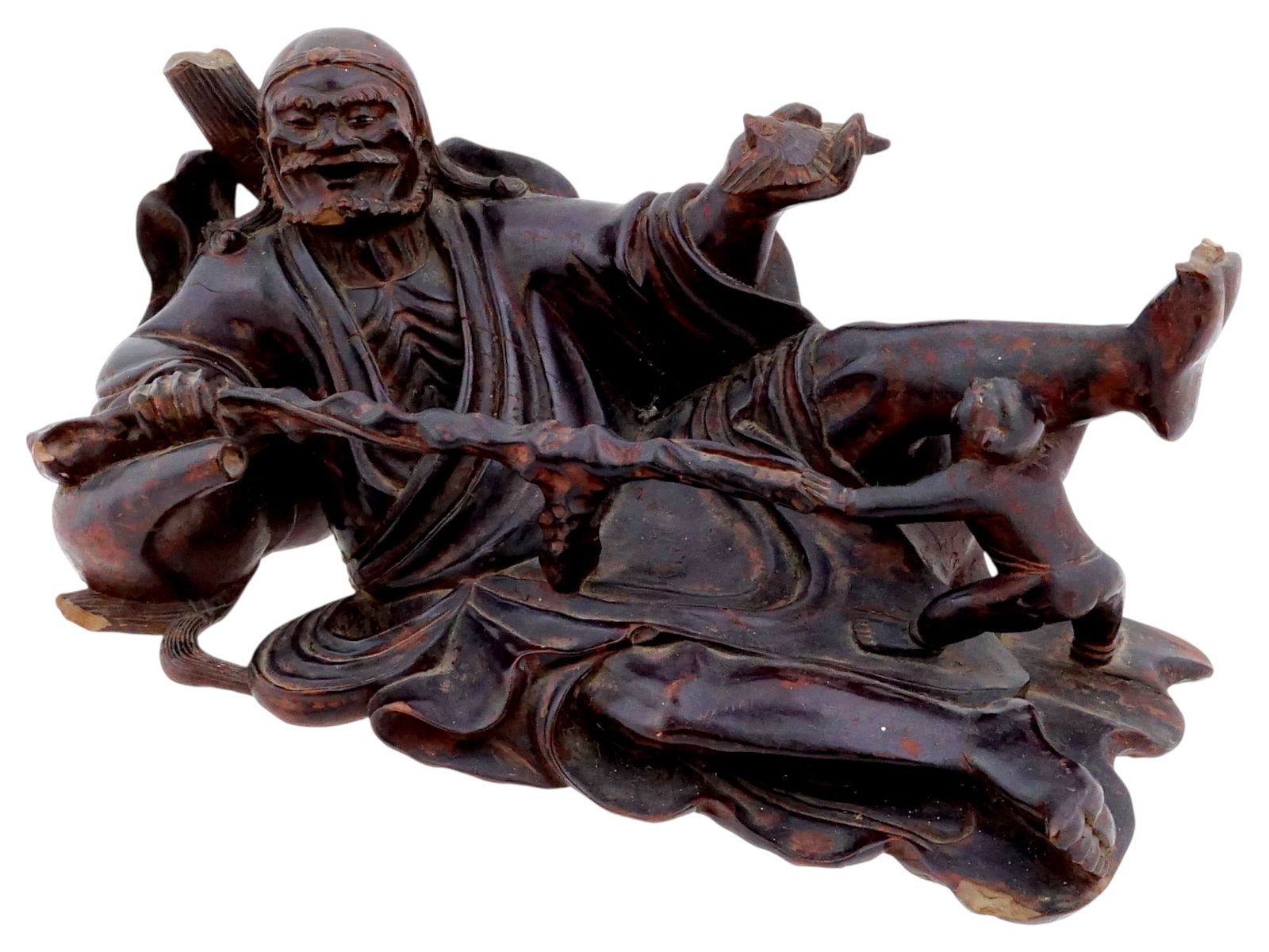 ANTIQUE CHINESE HARDWOOD CARVED IDOL FIGURINE: An antique Chinese hardwood carved idol figurine depicting a smiling, elderly bearded figure shown in a reclining pose with one leg extended, with a smaller figure holding it. Dating to the early 20th