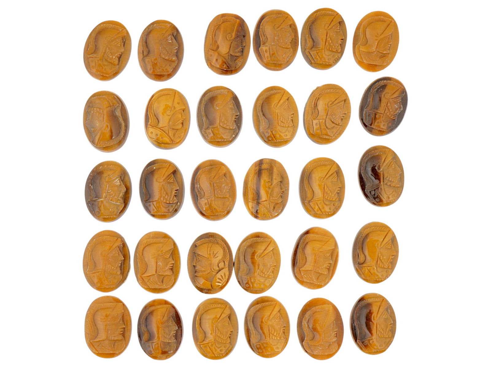 COLLECTION OF PORTRAIT CARVED TIGERS EYE CAMEOS: A collection of hand carved tigers eye cameos. A total of 30 items. Each piece features a knight profile portrait rendered in high relief. Oval shape. Collectible Jewelry And Glyptic Art, Sculpture.