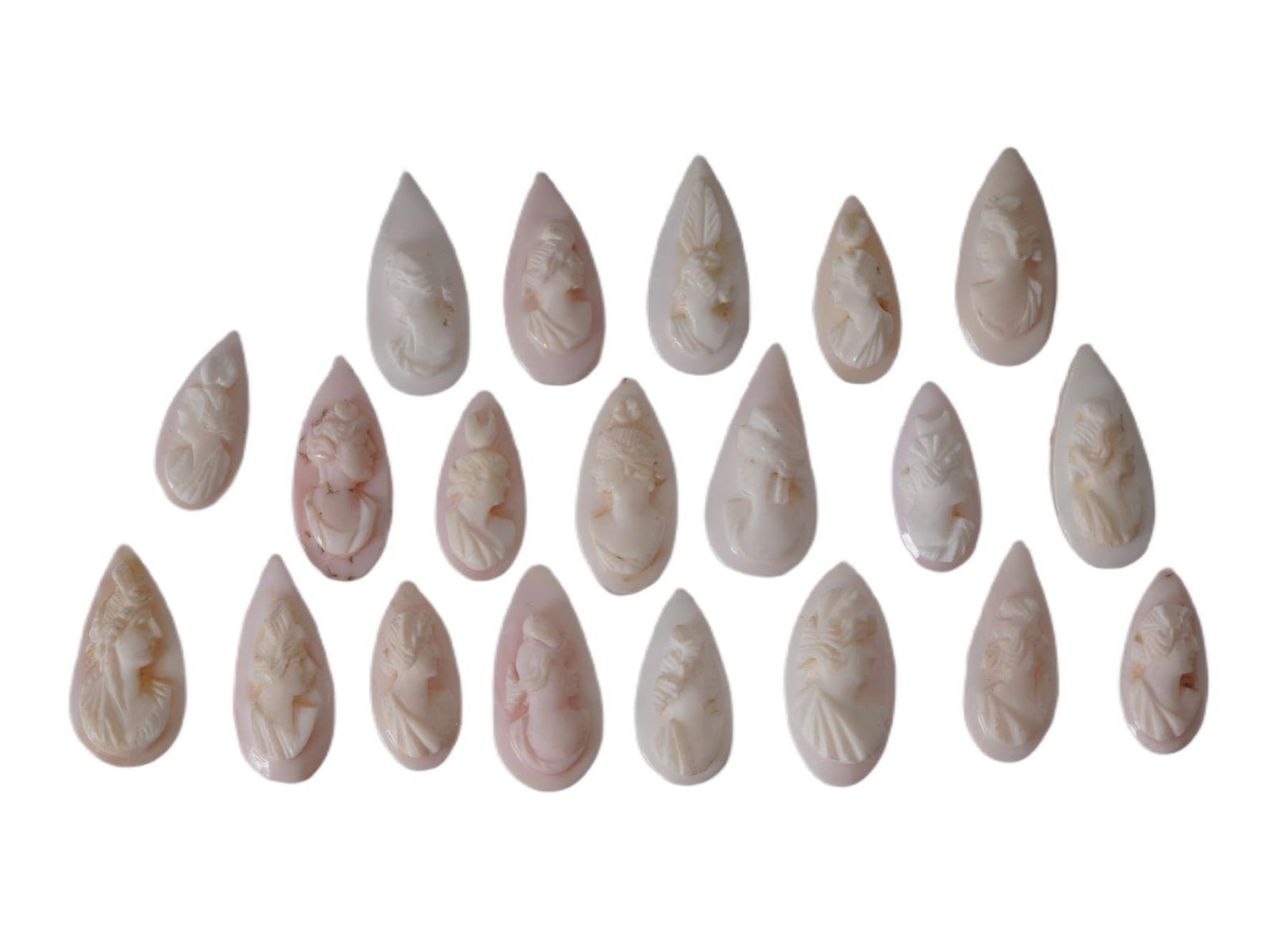 COLLECTION OF FEMALE PORTRAIT CARVED CORAL CAMEOS: A collection of hand carved pink coral cameos. A total of 20 items. Each piece depicts a female profile portrait rendered in high relief. Drop shape. Collectible Jewelry And Glyptic Art, Sculpture.