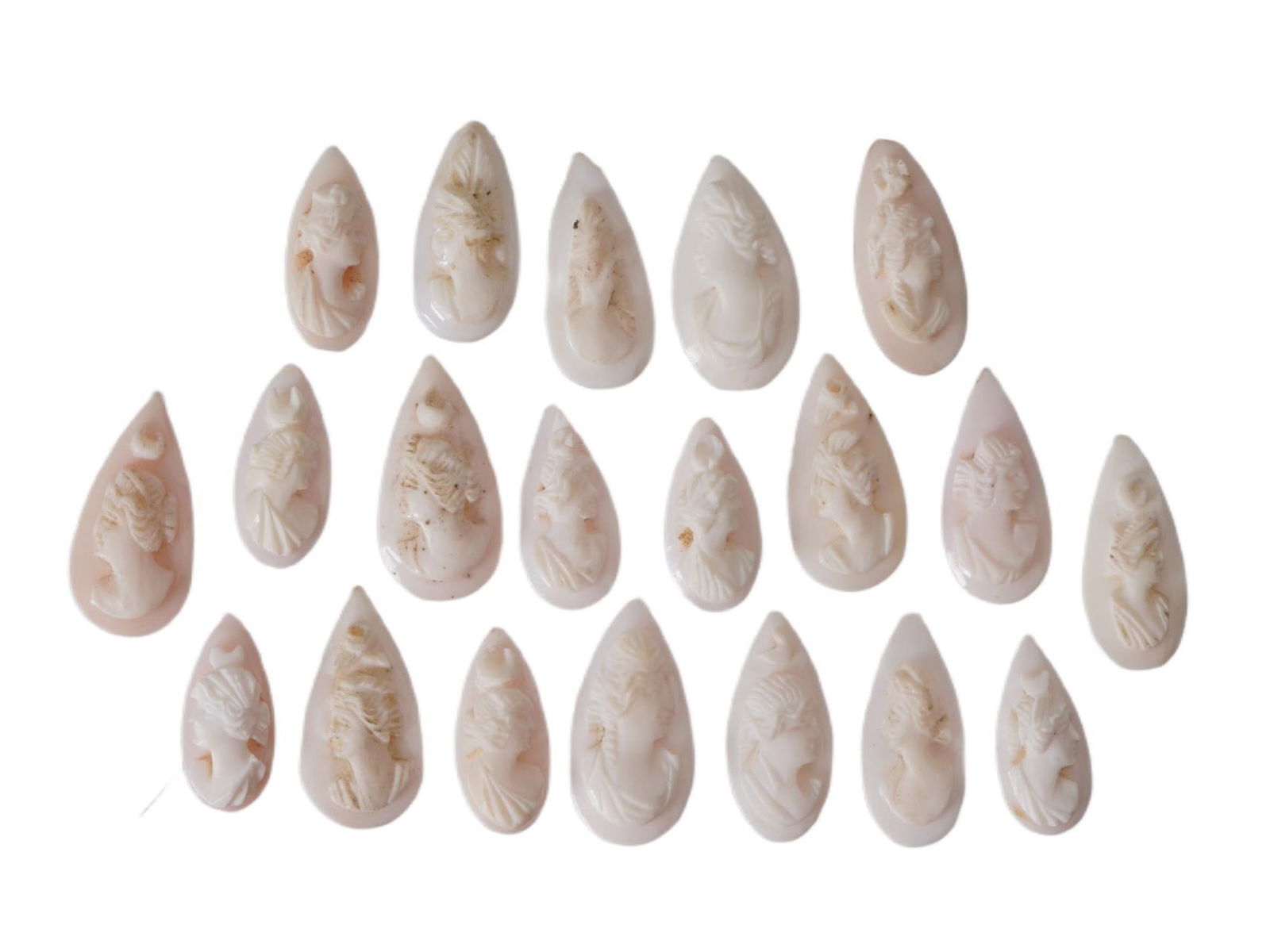 COLLECTION OF FEMALE PORTRAIT CARVED CORAL CAMEOS: A collection of hand carved pink and white coral cameos. A total of 20 items. Each piece depicts a female profile portrait rendered in high relief. Drop shape. Collectible Jewelry And Glyptic Art, Scu