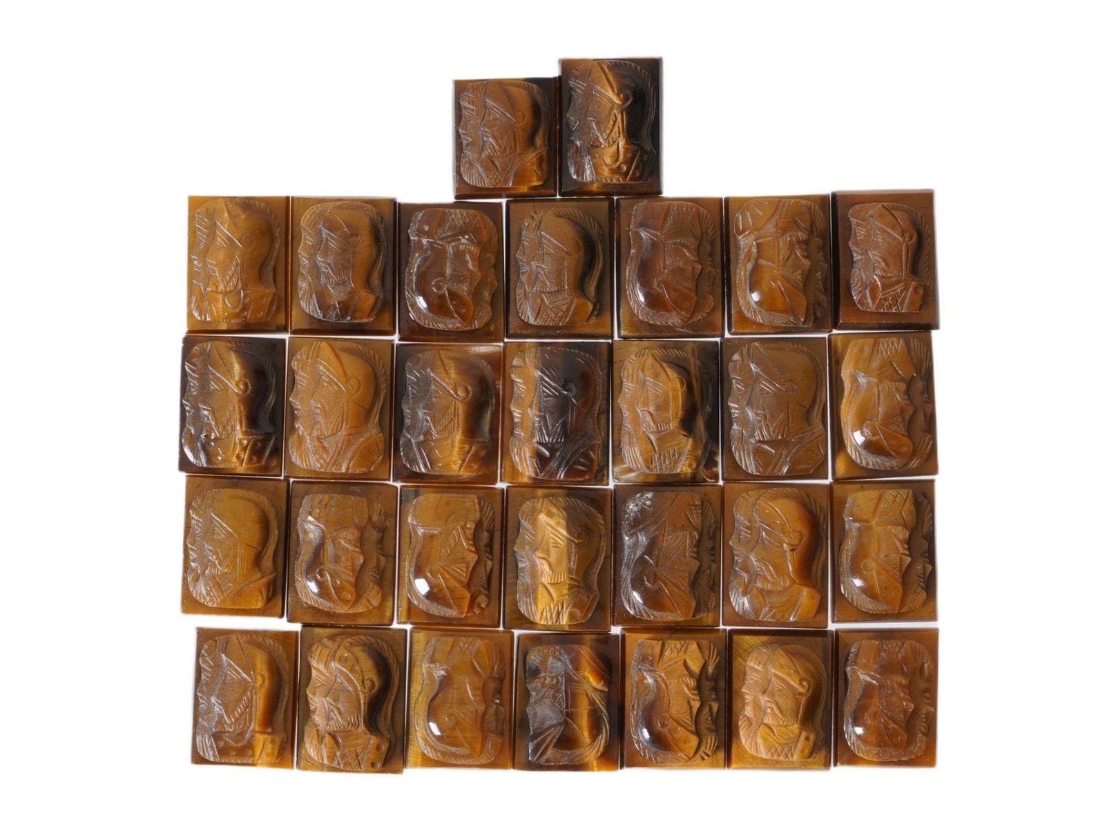 COLLECTION OF PORTRAIT CARVED TIGERS EYE STONE CAMEOS: A collection of thirty hand carved stone cameos. Each depicts a profile bust in relief, identified as Roman soldiers, warriors. Carved from natural tigers eye stone. The cameos are formed as small rec