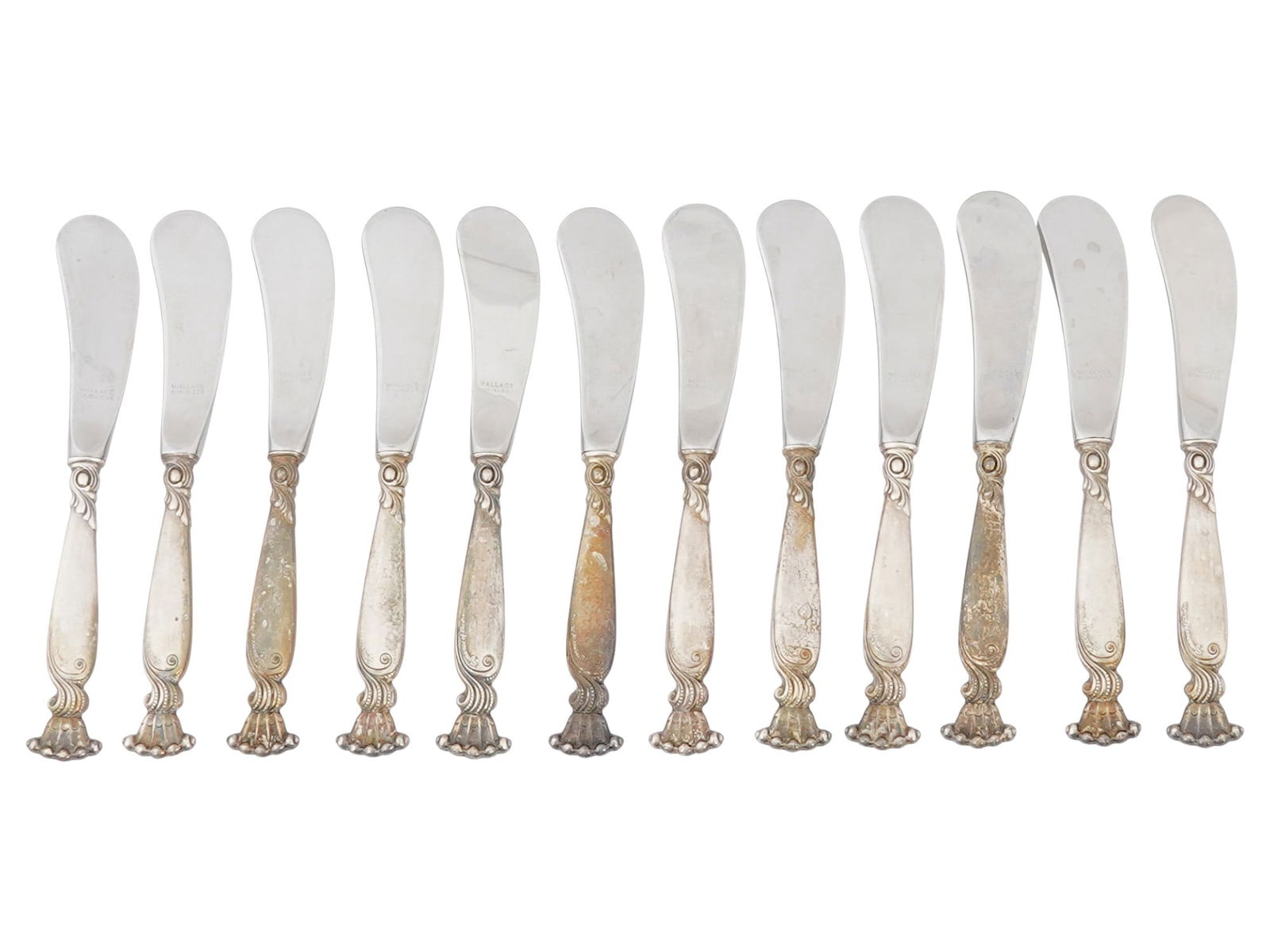 WALLACE ROMANCE OF THE SEA STERLING SILVER BUTTER KNIVES: A set of 12 vintage butter knives or spreaders by Wallace Silversmiths, an American manufacture established in 1835. Romance of the Sea collection. Sterling silver handles in shell patern, marked with
