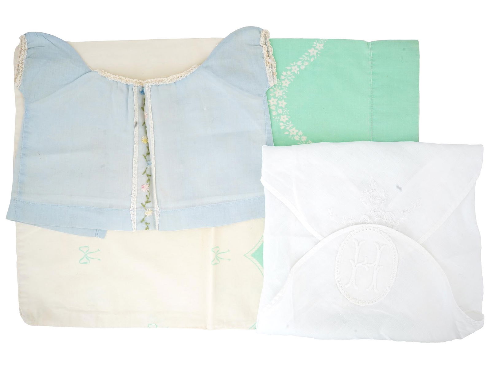 ANTIQUE AND VINTAGE BABY EMBROIDERED TEXTILE: A collection of antique and vintage baby items features a pastel colored assortment of textiles, including a light blue top trimmed with lace and embroidered with delicate floral designs, a mint green