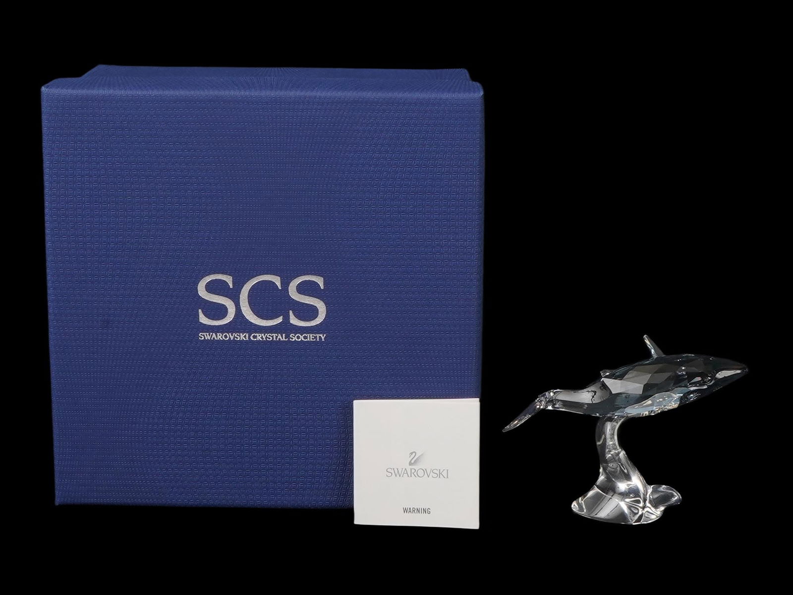 SWAROVSKI SCS 2012 EDITION YOUNG WHALE PAIKEA FIGURE: A Swarovski SCS Young Whale Paikea figurine, designed by Stefanie Nederegger and issued as the 2012 Annual Edition companion piece. Crafted in Shadow crystal with Crystal Moonlight fins, the Young Hum