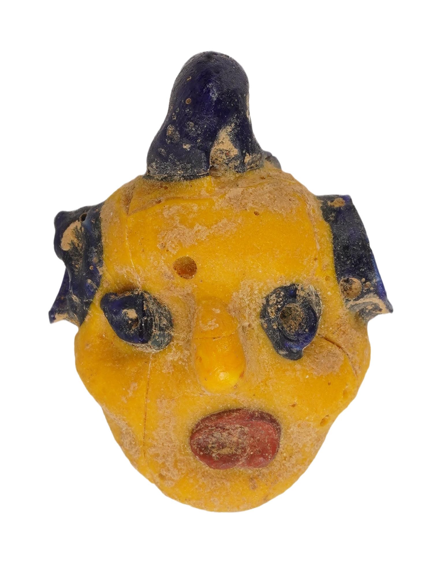 GRECO ROMAN MULTICOLORED MOSAIC GLASS AMULET PENDANT: A Greco Roman multicolored mosaic glass amulet pendant, artfully crafted in the shape of a head in yellow, blue and red. Circa 300 BC to 100 BC. This artifact showcases the remarkable artistry and cul