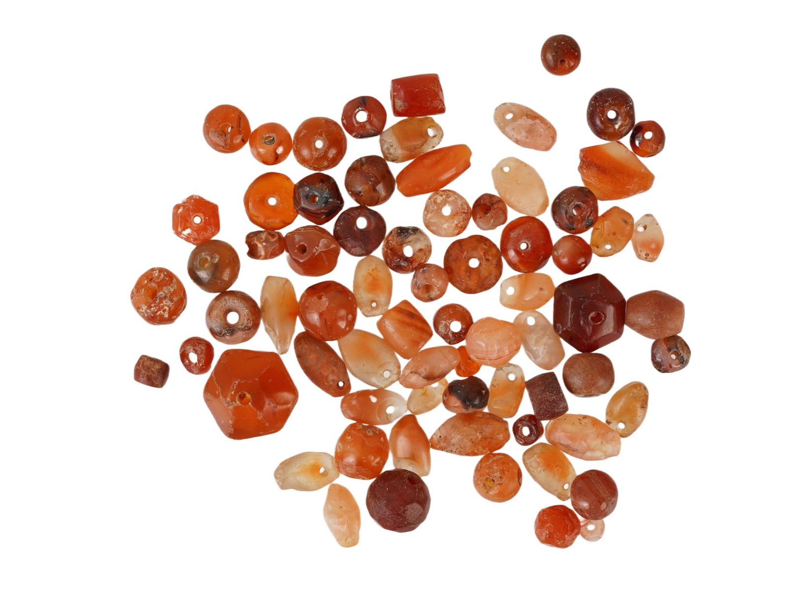 GROUP OF ANCIENT CARNELIAN BEADS OF VARIOUS SHAPES: A group of ancient carnelian beads of various shapes, dating from the 1st millennium BC through the Roman period. Comprising a varied assortment of polished stone examples in warm reddish-orange tones