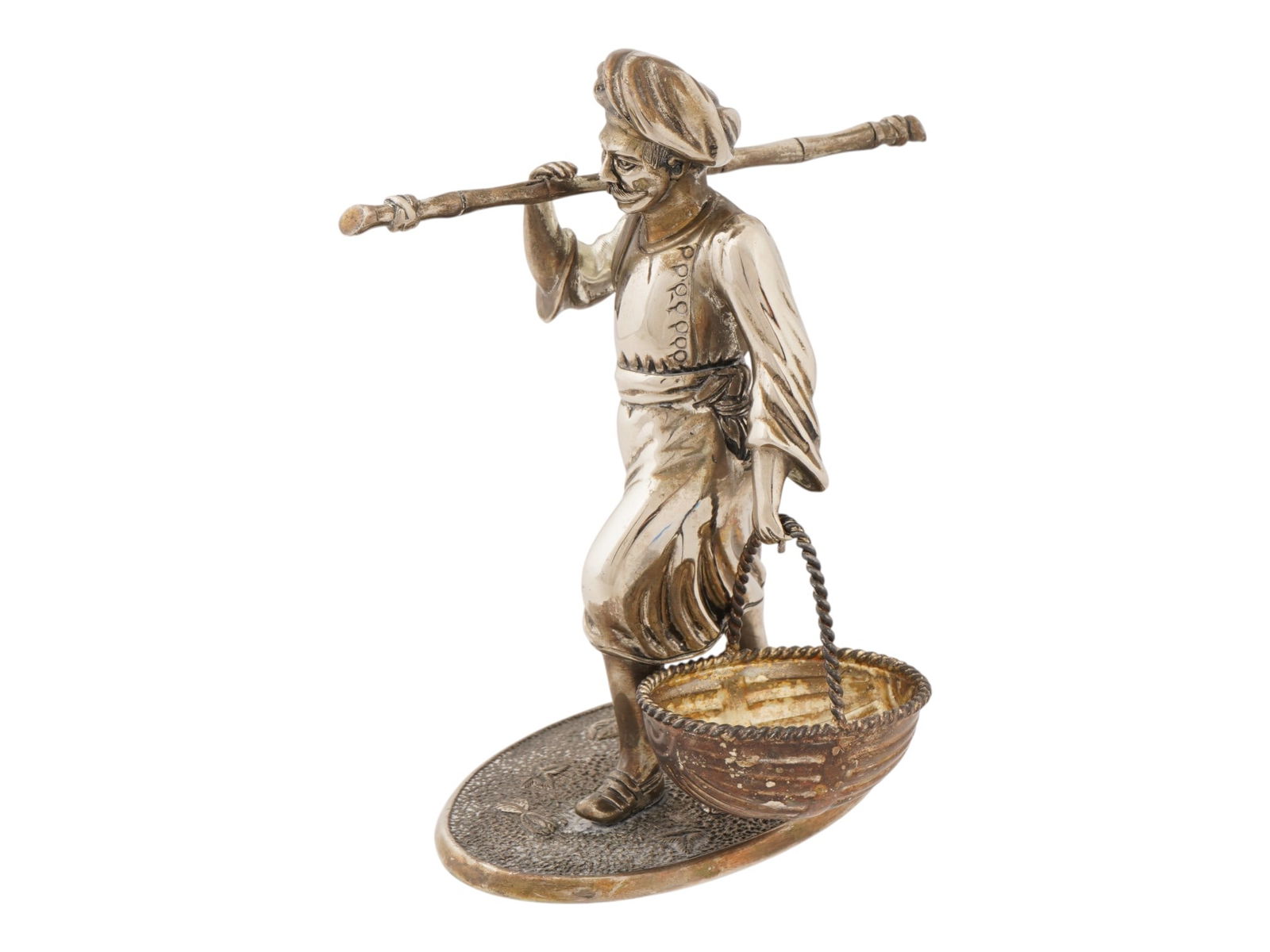 VINTAGE INDIAN BOMBAY COMPANY CAST METAL FIGURINE: A vintage Indian Bombay Company cast metal figurine. The figurine depicts an Indian farmer wearing a turban, holding a basket and a stick over his shoulder. It is mounted on an oval base with a textur