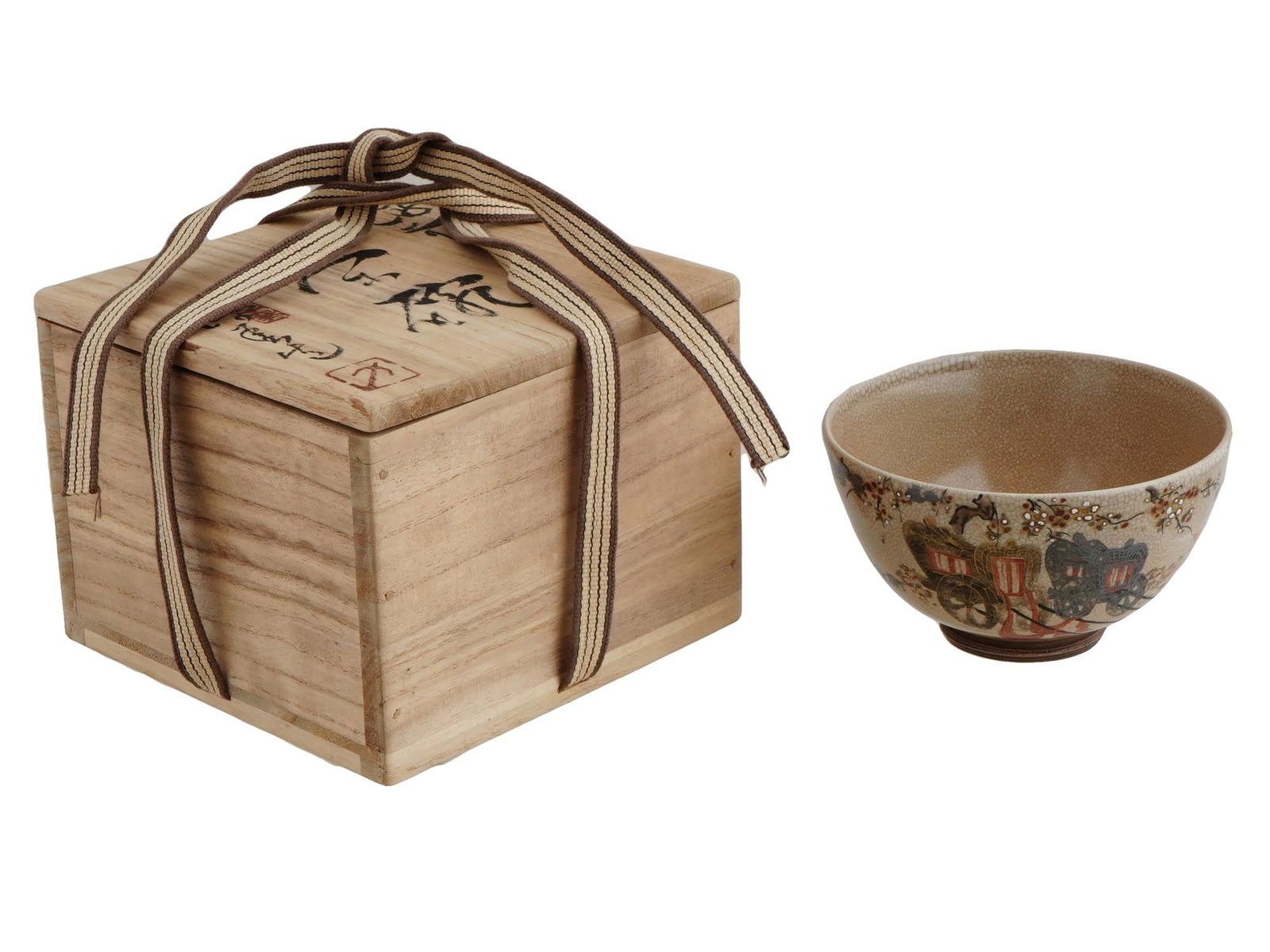 JAPANESE HAND PAINTED POTTERY TEA BOWL WITH WOOD BOX: A Japanese footed pottery tea bowl. The exterior of the ware is covered with glaze in a beige shade, and adorned with a hand painted design representing a carriage and a floral motif. The ware is