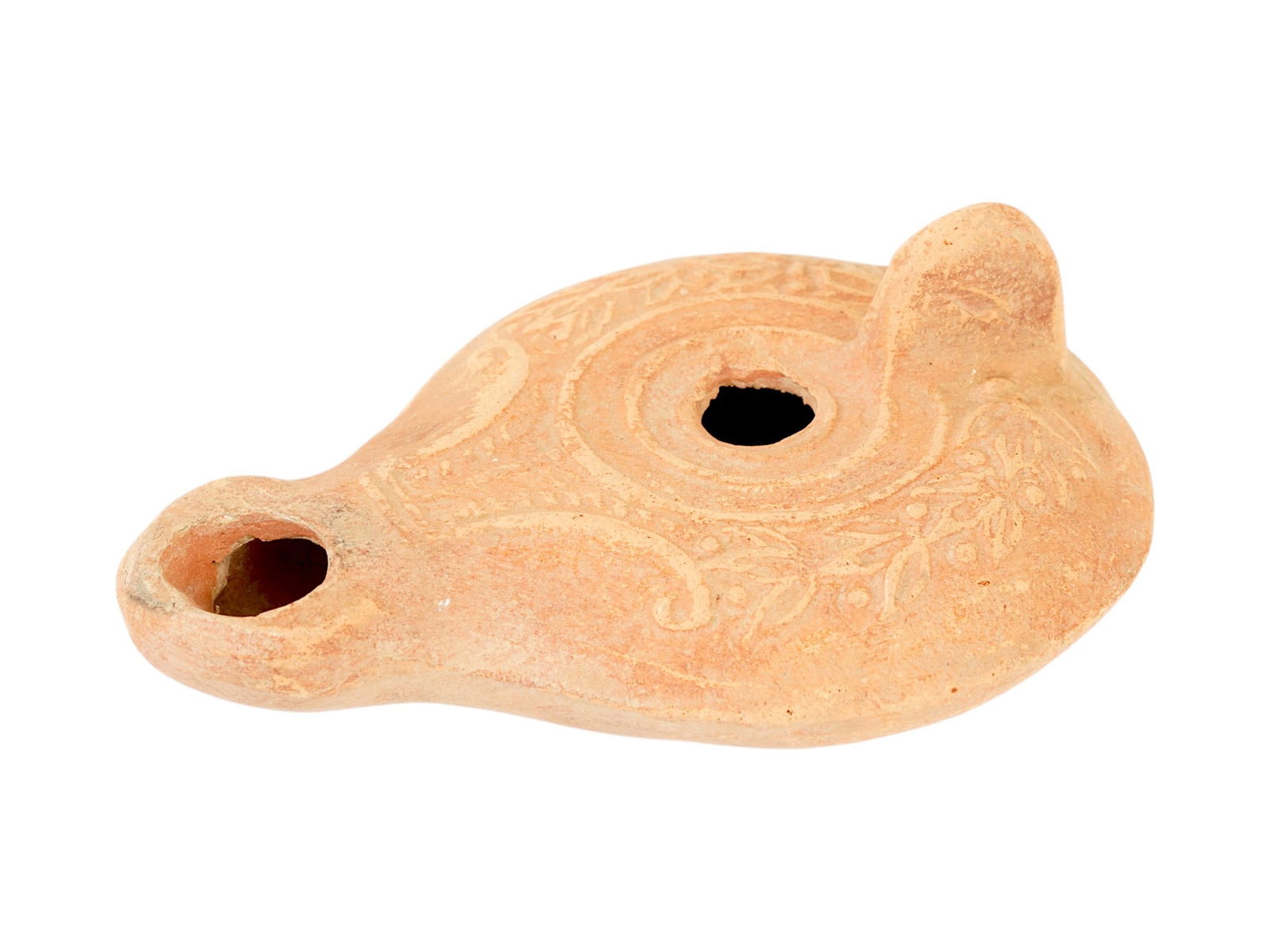 ANCIENT ROMAN LOTUS TERRACOTTA OIL LAMP 100 TO 300 AD: An ancient Roman terracotta pottery oil lamp. The body of the lamp is adorned with an embossed lotus floral design on the shoulders. The lamp is decorated with a raised circle nozzle top and a raised