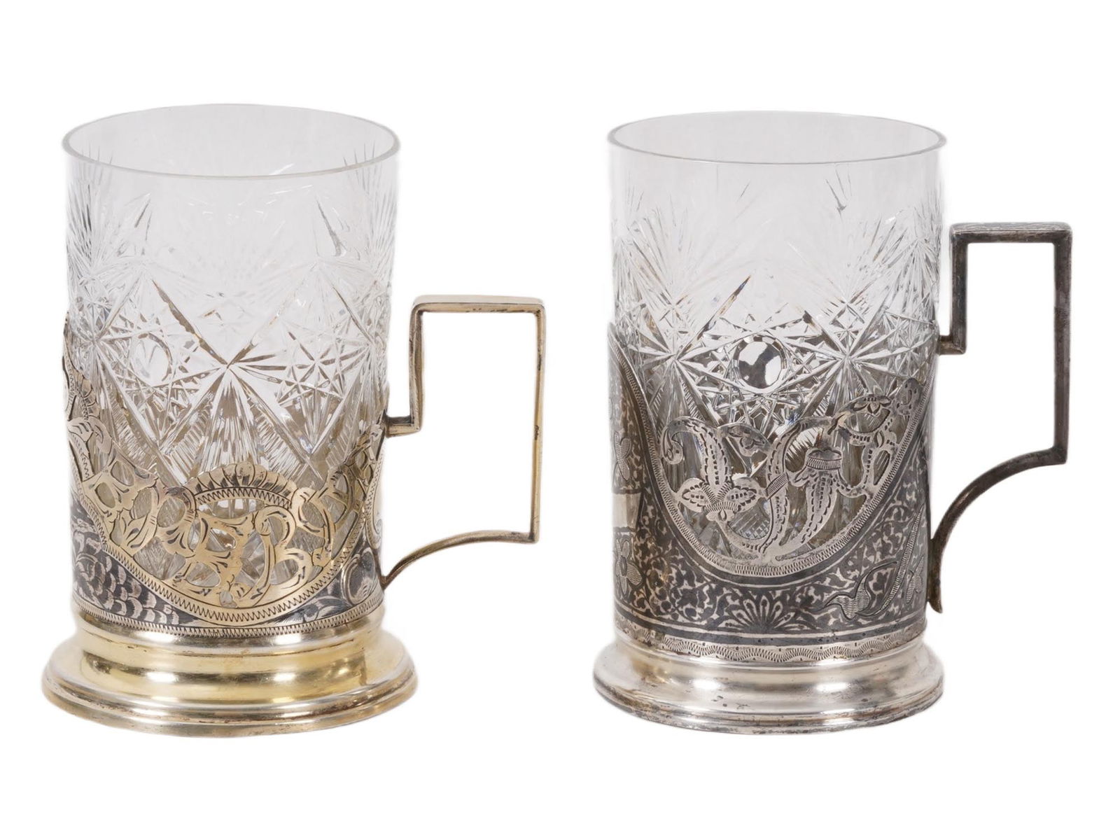 RUSSIAN SOVIET SILVER NIELLO GLASS HOLDERS WITH INSERTS: A pair of Russian Soviet gilt silver and niello tea glass holders with crystal inserts, traditionally known as podstakanniks, a term that literally translates to thing under the glass. These holders a