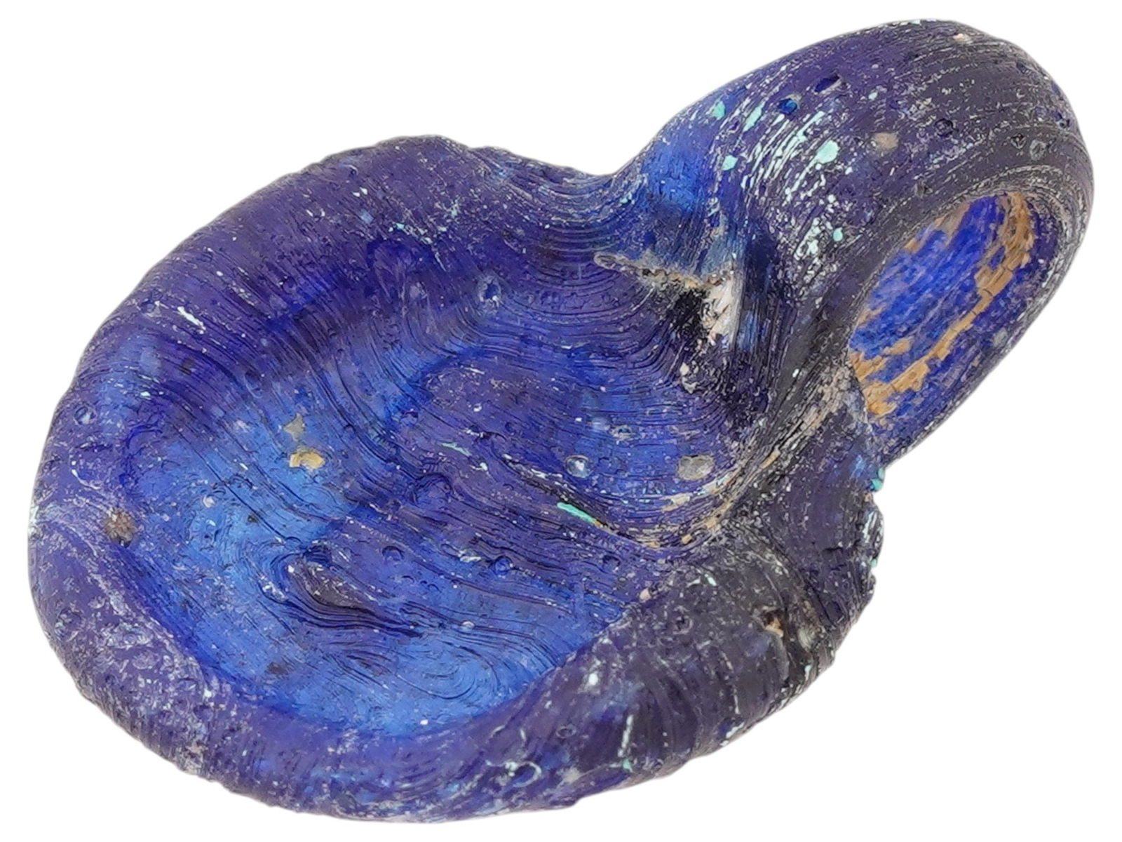 ANCIENT ROMAN BLUE GLASS PENDANT WITH A LION MOTIF: An ancient Roman blue glass pendant, dating circa 100 to 300 AD, features a rendered lion motif associated with astrological symbolism. Crafted in vivid translucent blue glass, the piece reflects the