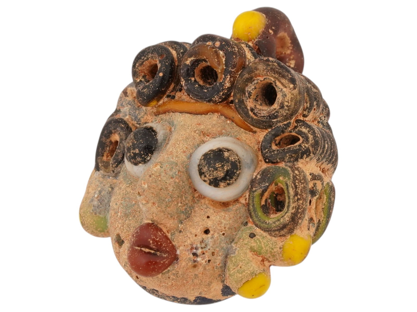 GRECO ROMAN MOSAIC GLASS AMULET PENDANT 300 TO 100 BC: A Greco Roman multicolored mosaic glass amulet pendant, artfully crafted in the shape of a head. Circa 300 BC to 100 BC. This artifact showcases the remarkable artistry and cultural significance of it