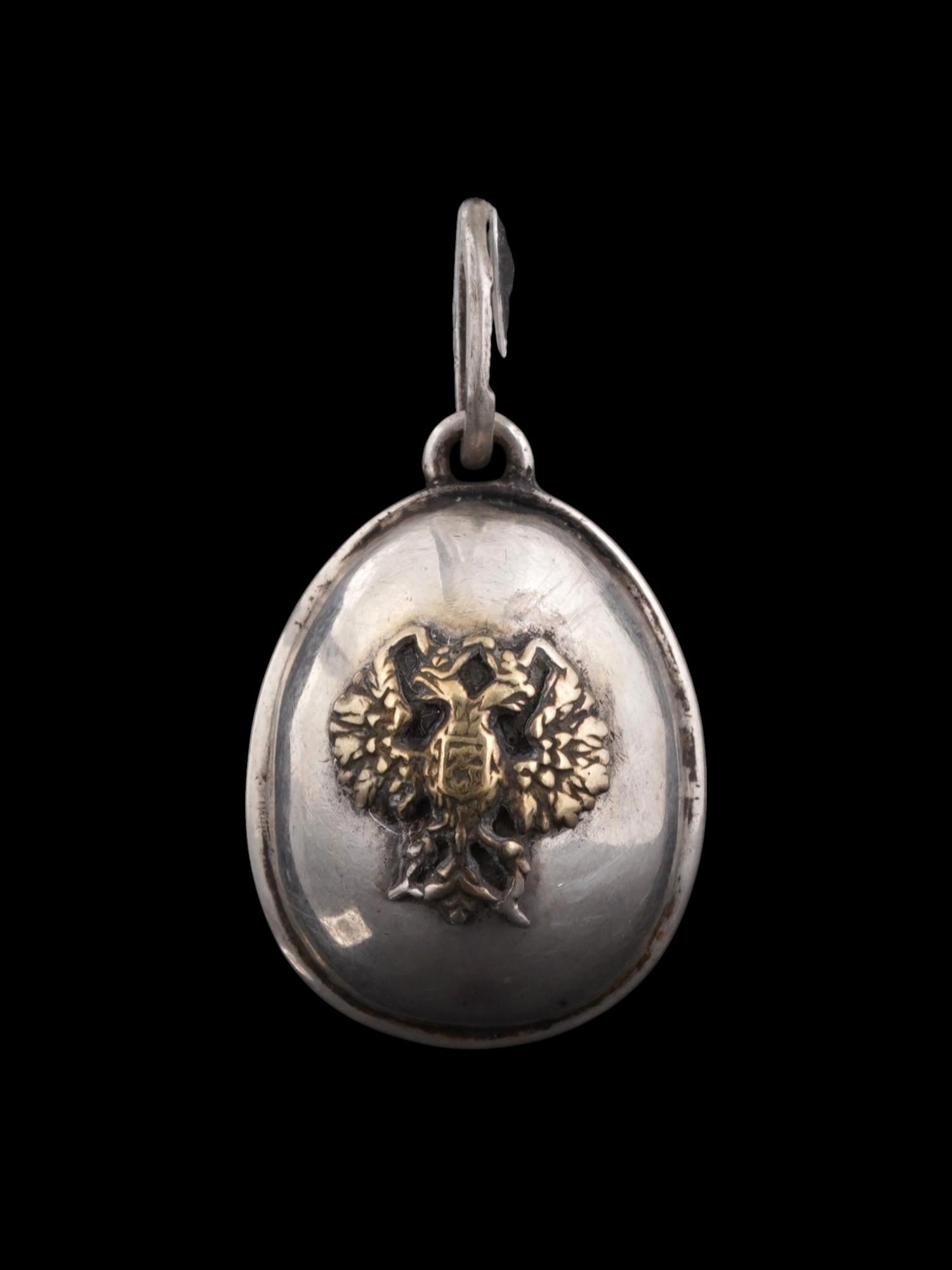 RUSSIAN SILVER IMPERIAL PRESENTATION EASTER EGG PENDANT: A Russian silver Imperial presentation Easter egg pendant featuring an applied gilt monogram of Tsar Nicholas II surmounted by the Imperial crown on the one side and a Double Headed Imperial Eagle on