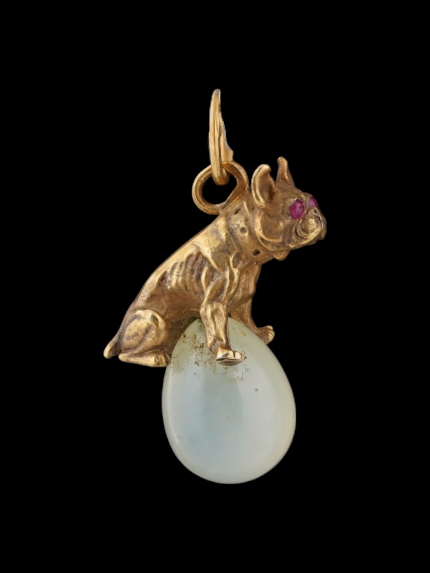 RUSSIAN GILT SILVER BOWENITE RUBY DOG EGG PENDANT: A Russian gilt silver bowenite egg dog shaped pendant. The egg is hand carved from natural bowenite stone and adorned with a figurative gilt silver upper part, modeled as a dog set with ruby eyes.