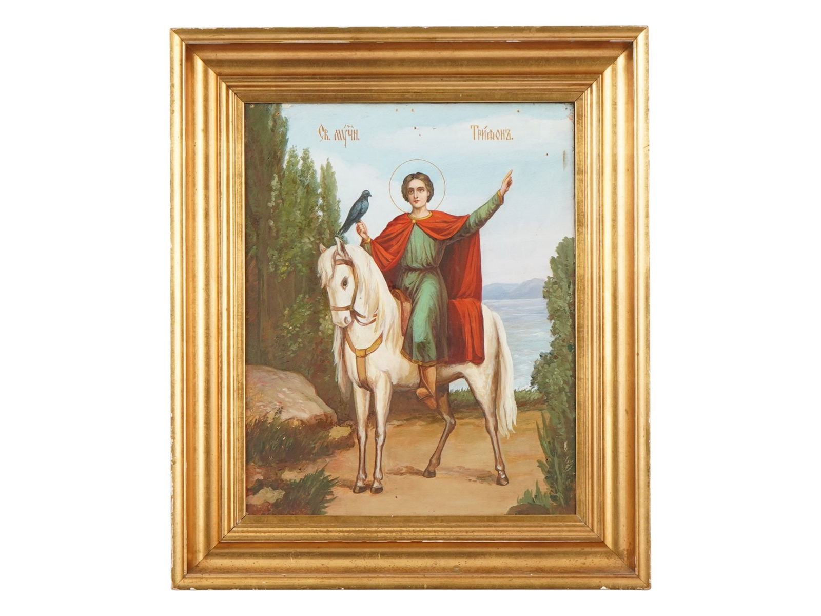 ANTIQUE 19TH C RUSSIAN ORTHODOX SAINT TRYPHON ICON: An antique, 19th century Russian Orthodox icon of Saint Tryphon. The saint is depicted according to his iconography, riding a horse and holding a hunting bird in his hand. Golden frame. Saint Tryphon