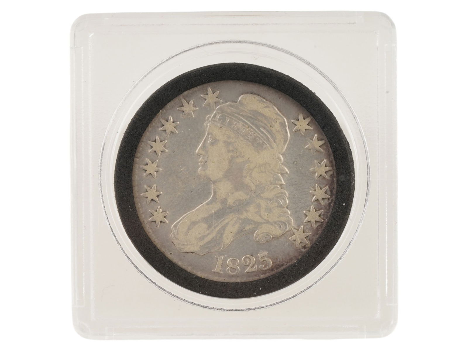 ANTIQUE 1825 SILVER CAPPED BUST HALF DOLLAR COIN: An antique 1825 silver Capped Bust Half Dollar coin. The coin features a portrait of Lady Liberty wearing a cap on the obverse and an eagle with a shield on the reverse. 1825 Capped Bust Half Dollar
