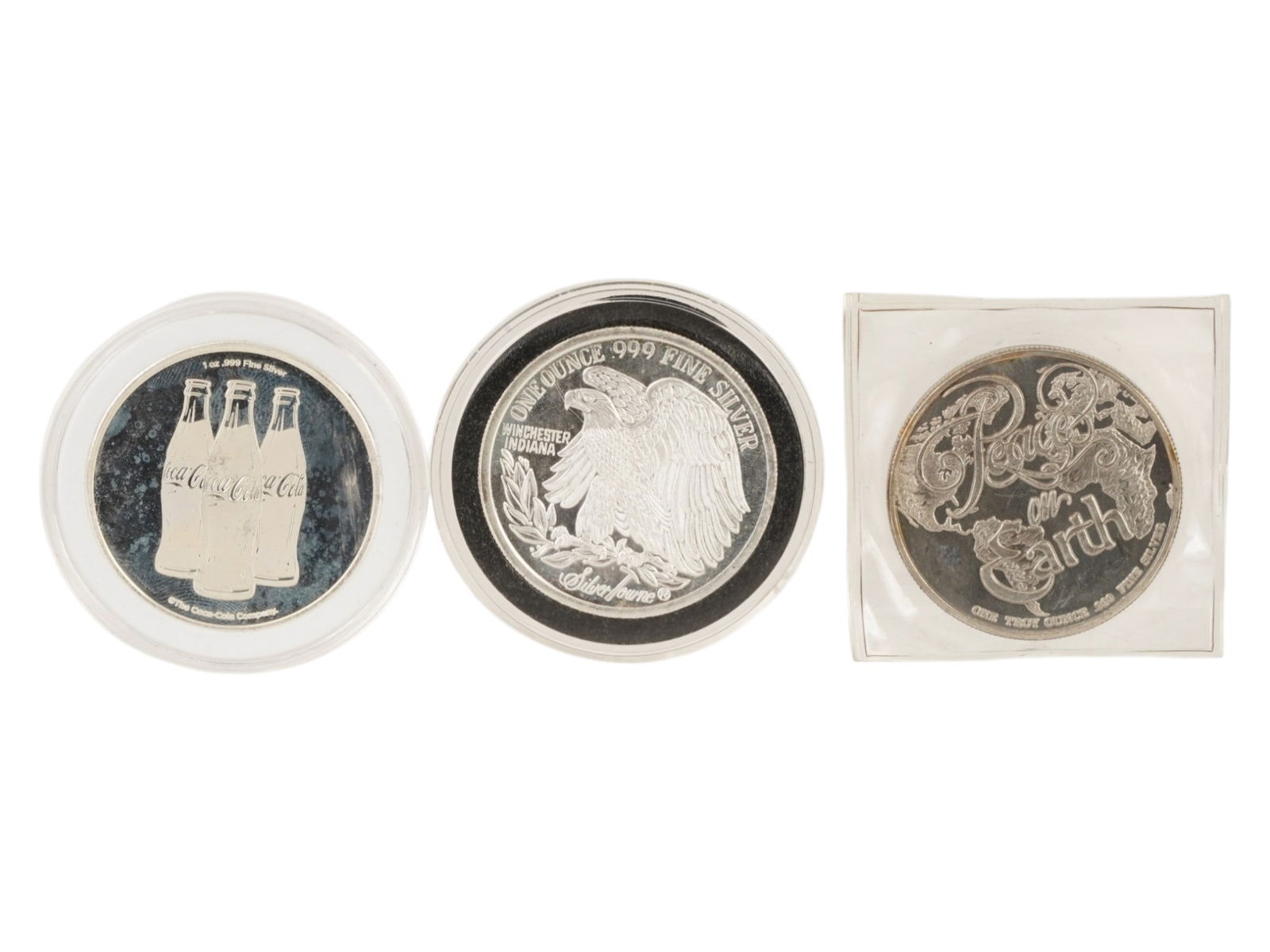 THREE VINTAGE ASSORTED 1 OZ .999 FINE SILVER ROUNDS: Three vintage assorted 1 oz .999 fine silver rounds, each struck in one troy ounce of pure silver. The group features a Coca-Cola themed round, a Peace on Earth commemorative design, and a classic