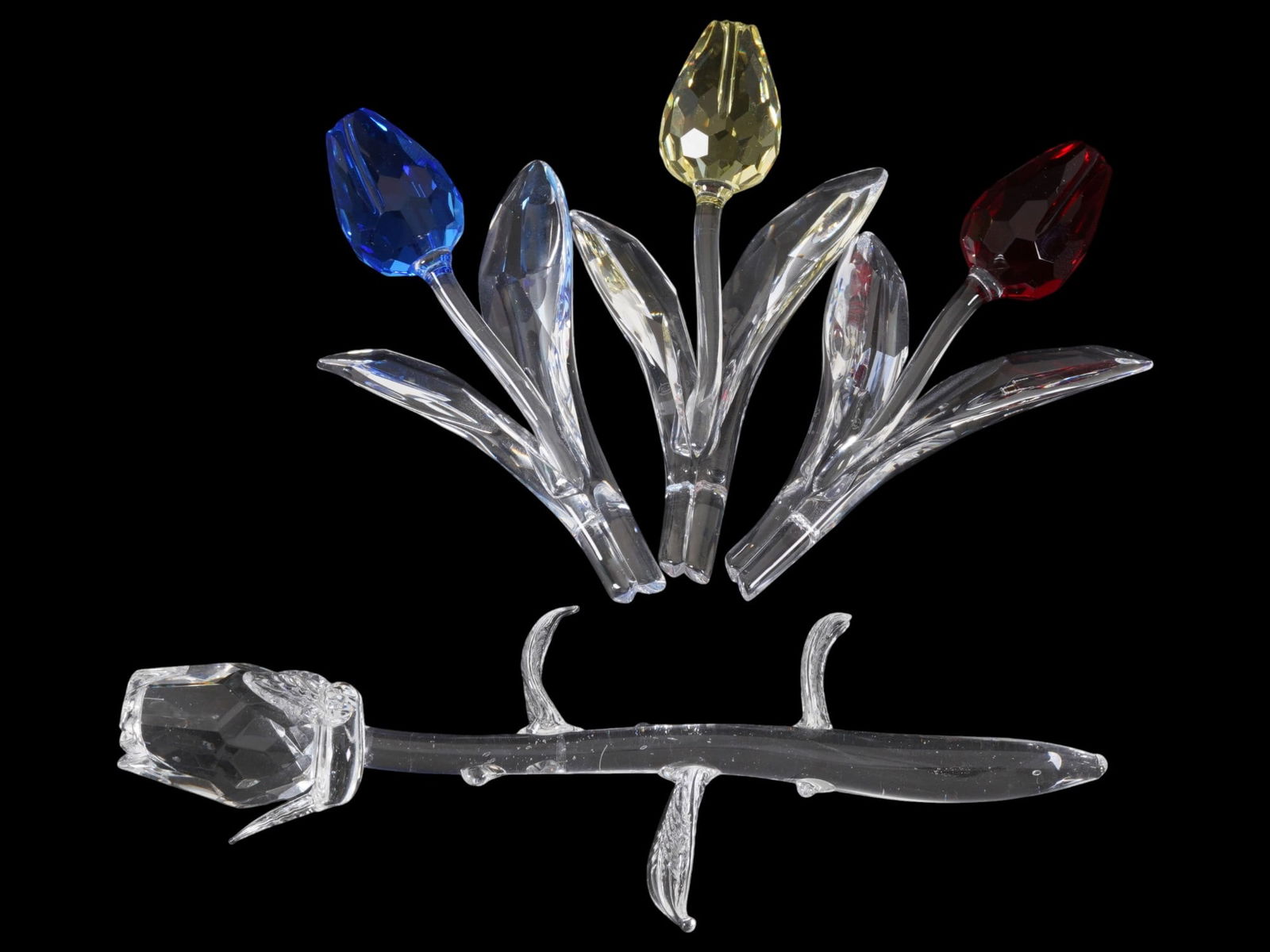 SWAROVSKI SET OF FOUR CRYSTAL TULIP AND ROSE: A set of collectible crystal tulip and rose figurines by the Austrian luxury brand Swarovski. This set features three large tulips and one rose with vibrant faceted crystal buds in blue, yellow, red a