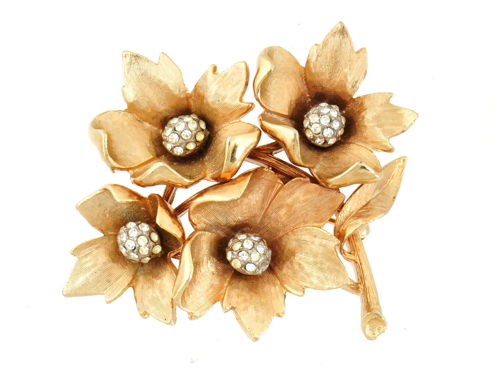 MID 20TH CEN FLORAL DESIGN COSTUME JEWELRY BROOCH: A Mid 20th century costume jewelry brooch. The brooch is made in a figural floral design, concentric circles with satin gold colored structure and rhinestones to the center. Each flower is adorned wit