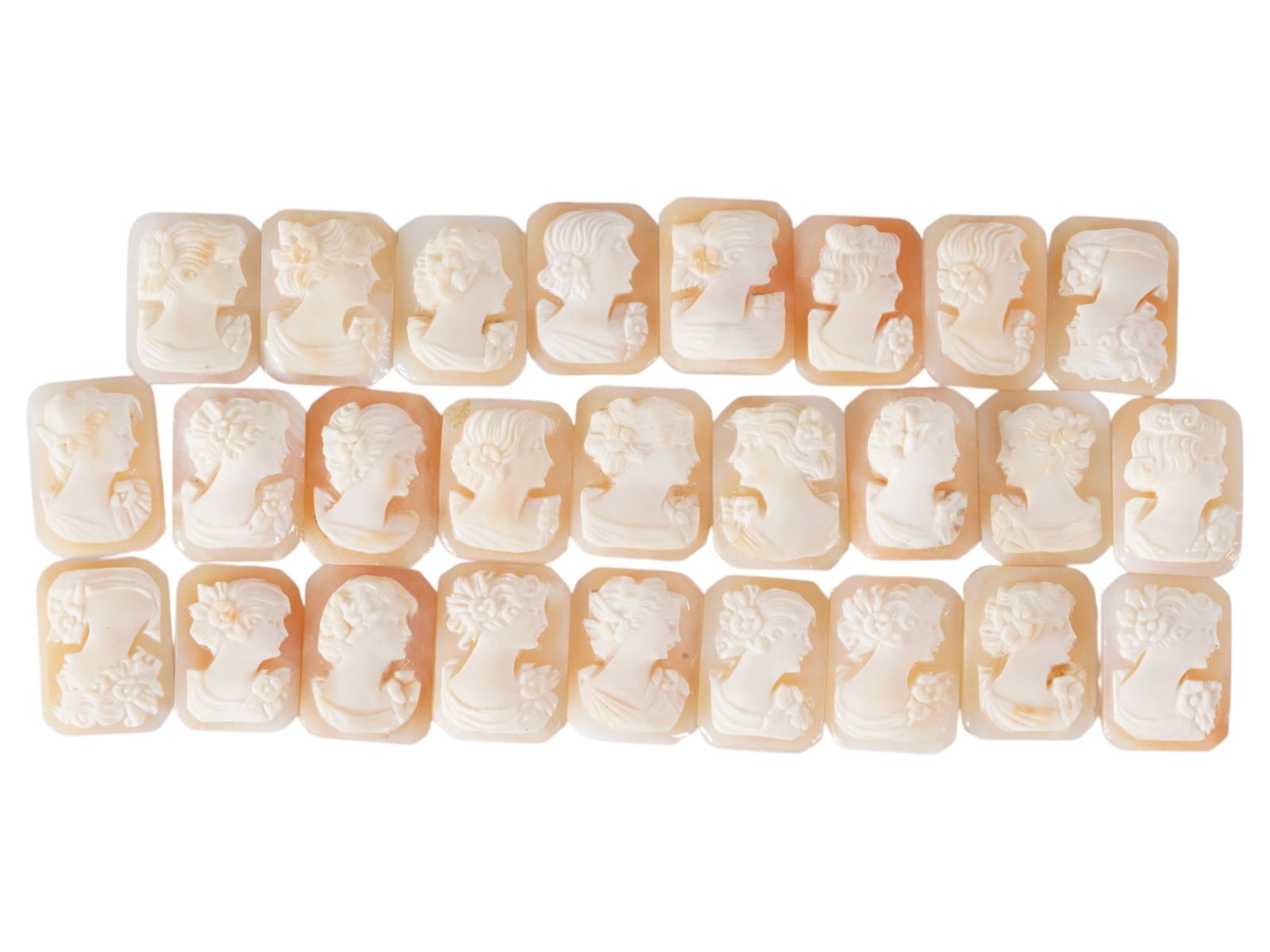 COLLECTION OF CARVED FEMALE PORTRAIT SHELL CAMEOS: A collection of hand carved shell cameos. A total of 26 items. Each piece depicts a female profile portrait rendered in high relief in the Victorian manner. Each cameo is fashioned in a distinctive oc