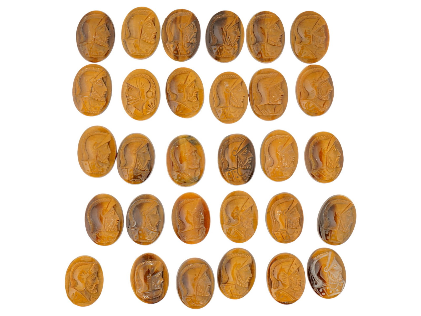 COLLECTION OF PORTRAIT CARVED TIGERS EYE CAMEOS: A collection of hand carved tigers eye cameos. A total of 30 items. Each piece features a knight profile portrait rendered in high relief. Oval shape. Collectible Jewelry And Glyptic Art, Sculpture.