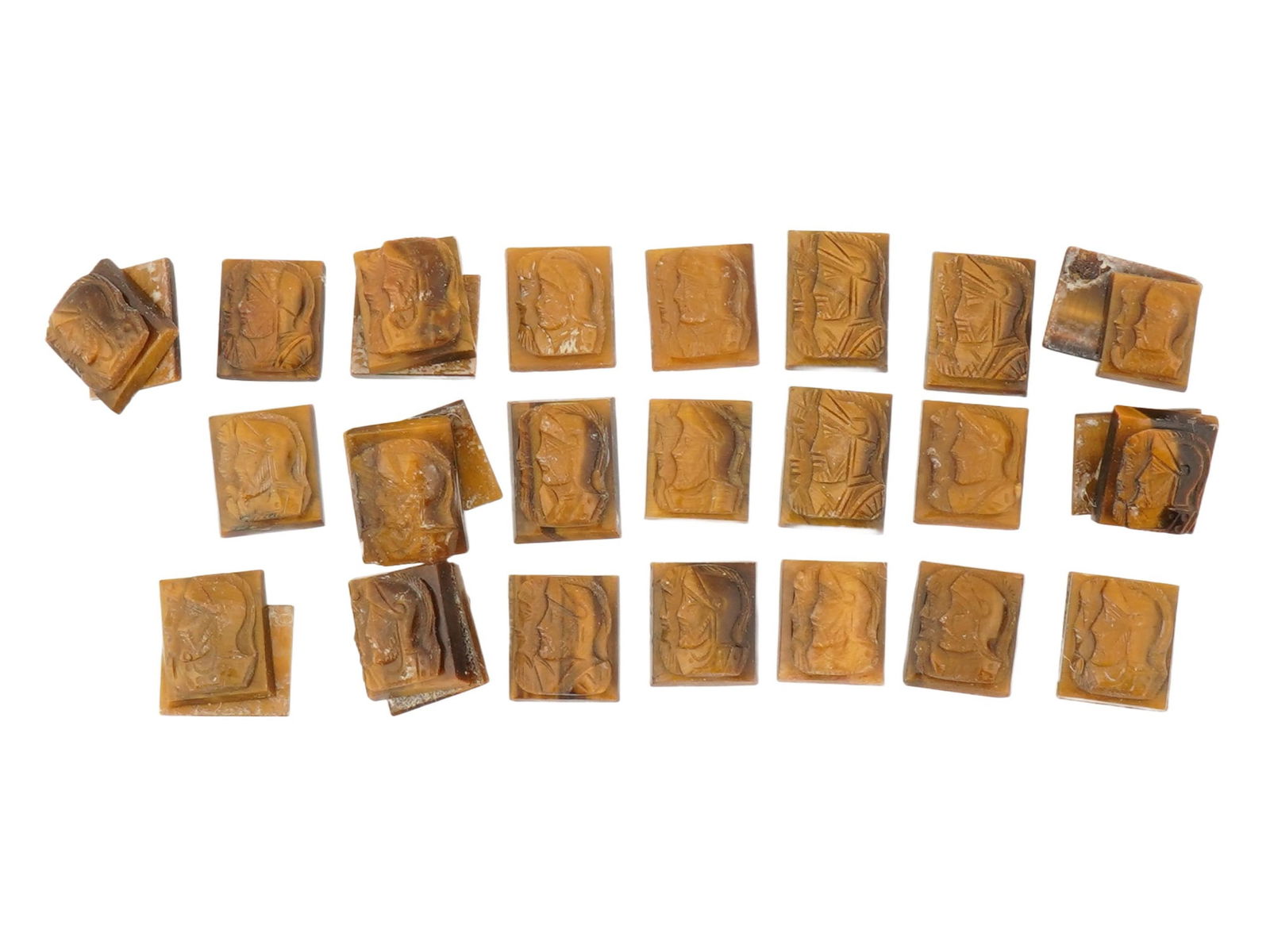 COLLECTION OF PORTRAIT CARVED TIGERS EYE STONE CAMEOS: A collection of 30 hand carved stone cameos. Each depicts a profile bust in relief, identified as Roman soldiers, warriors. Carved from natural tigers eye stone. The cameos are formed as small rectang