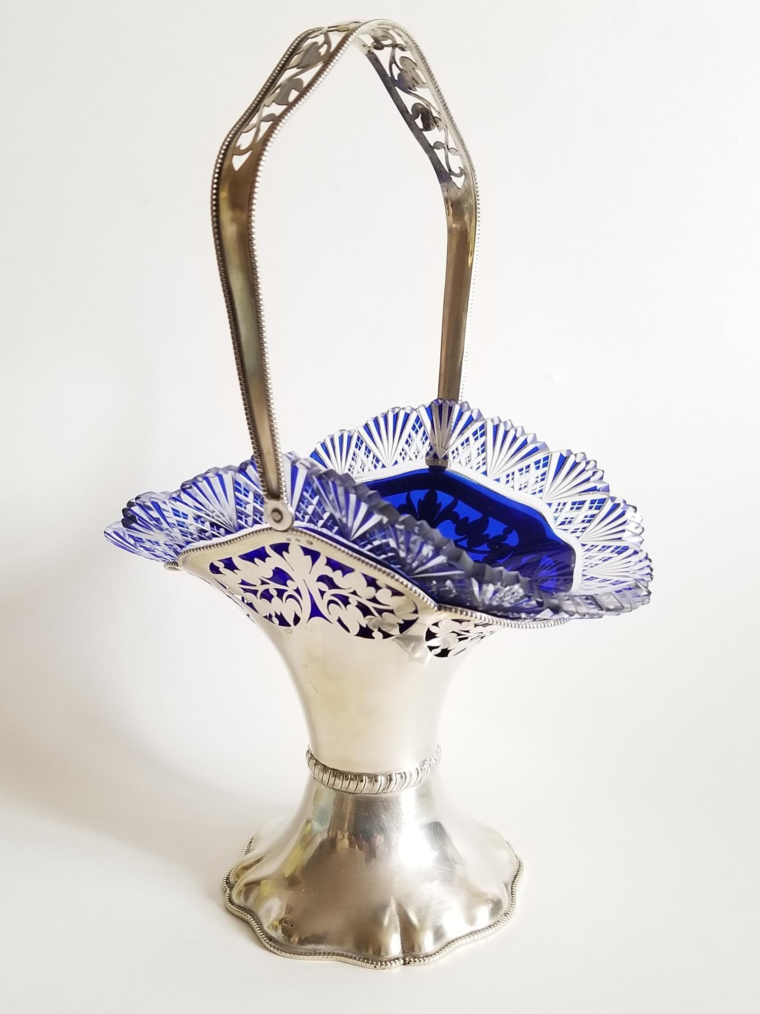 ANTIQUE STERLING SILVER BOHEMIAN COBALT GLASS BASKET: An antique Continental silver basket with Bohemian cobalt cut to clear crystal insert. The silver basket is decorated with a perforated design around the edge and handle. Hallmarked with an 800 silver