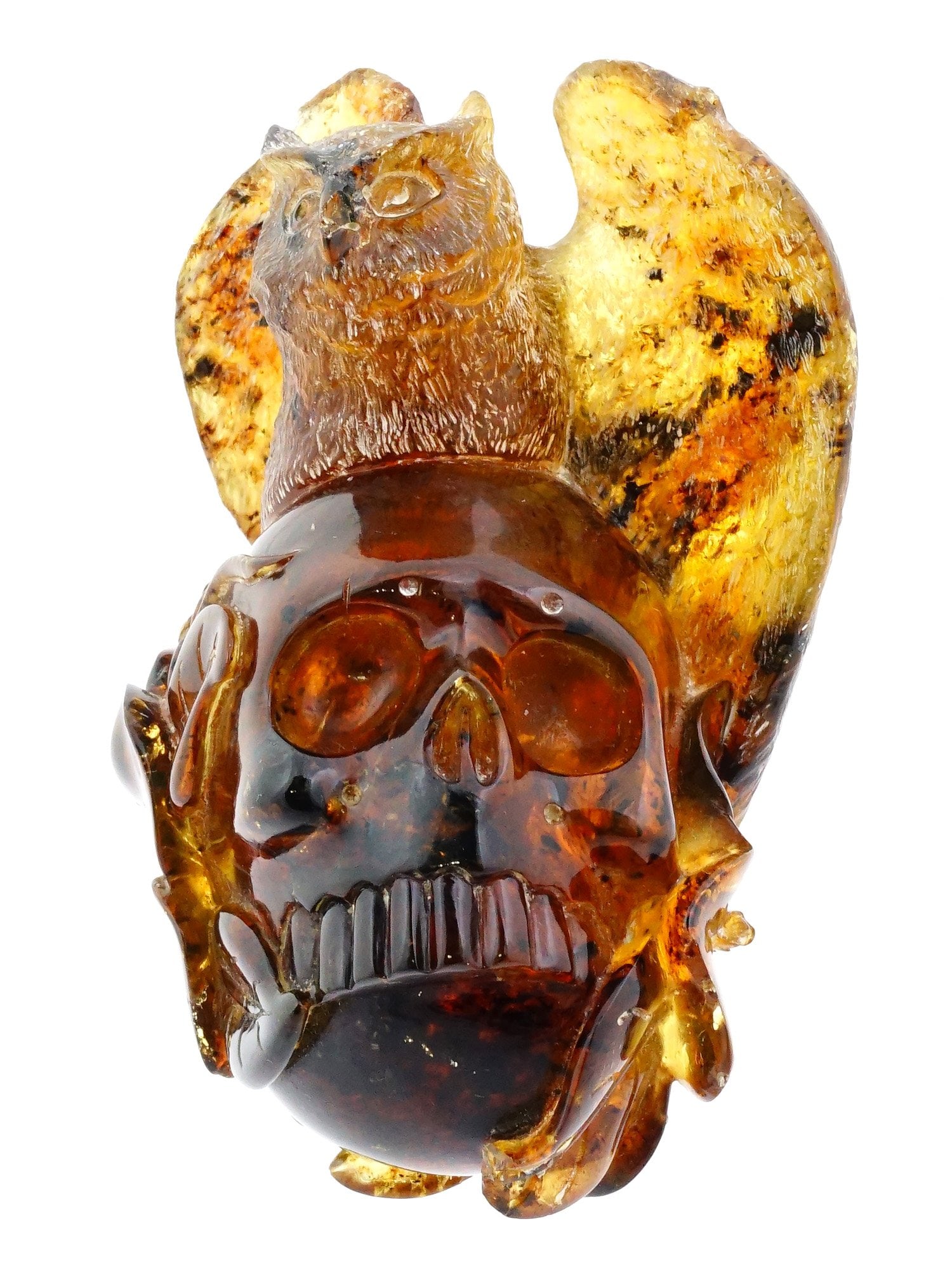 HAND CARVED NATURAL AMBER FIGURINE OF SKULL WITH OWL: A hand carved from natural Amber figure. The figure depicts a skull with an owl seated on the top. The sculpture is engraved with detailed patterns. Unsigned. Modernist and Contemporary Carved Natural