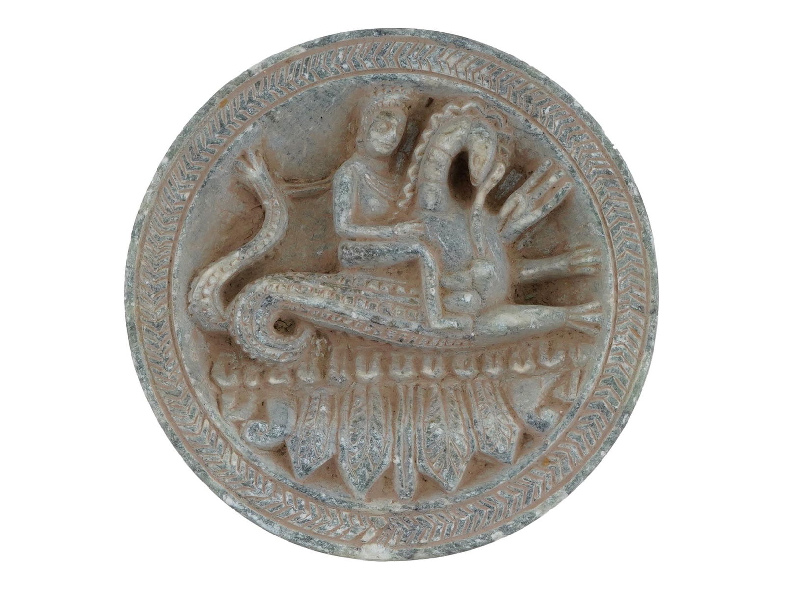 ANCIENT GANDHARAN CARVED STONE COSMETIC PALETTE: An ancient Gandharan carved stone cosmetic palette. Indo-Greek period, 180 BC to 10 AD. The round palette features a relief image of a god riding a mythological animal at the top and a large foliate p