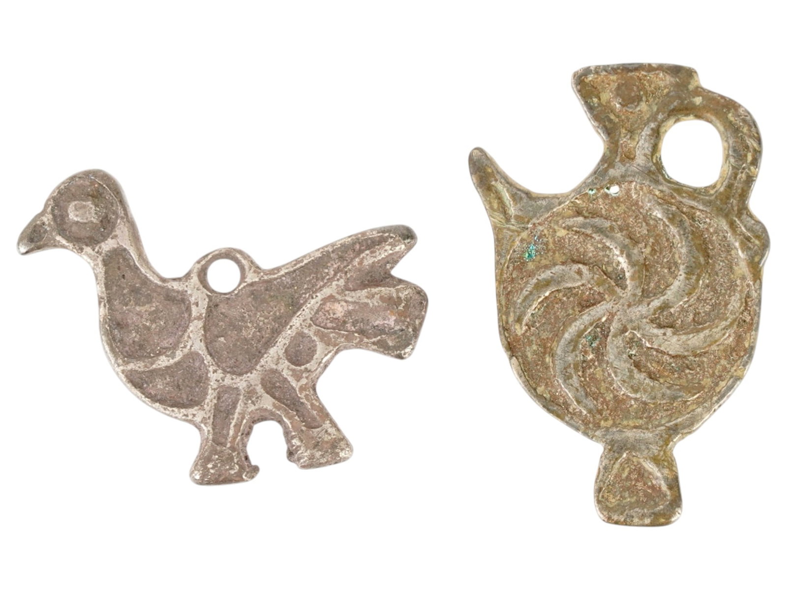 TWO BYZATHINE ISLAMIC SILVER PENDANTS 500 TO 800 AD: A lot of two Byzathine Islamic silver pendants, circa 500 to 800 AD. The first pendant is a common zoomorphic form, often identified as a dove or peacock. The flat, simplified profile with incised lin