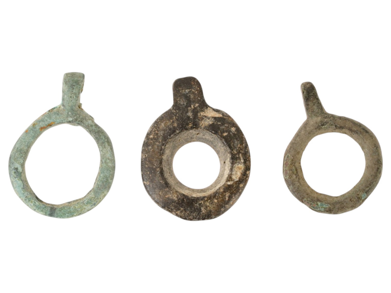 ANCIENT NEAR EASTERN SHELL AND BRONZE EYE IDOL PENDANTS: A group of three ancient Near Eastern eye idol pendants from the 2nd to 1st millennium BC, consisting of one carved shell example and two cast bronze versions, each featuring a suspension loop. Ancien